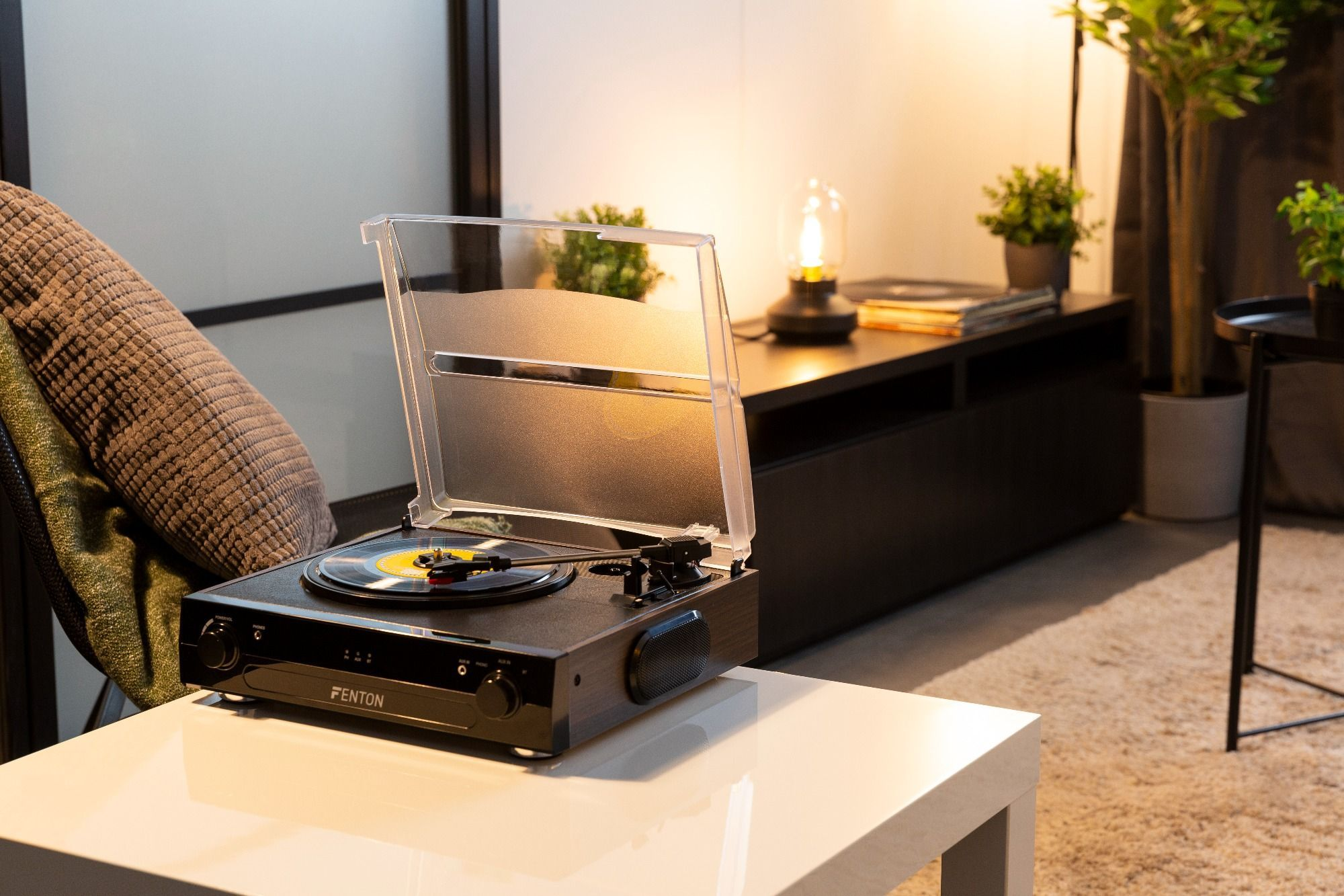 Schwarzer Plattenspieler auf weißem Tisch. Vinyl-Schallplatte darauf. Wohnzimmer.