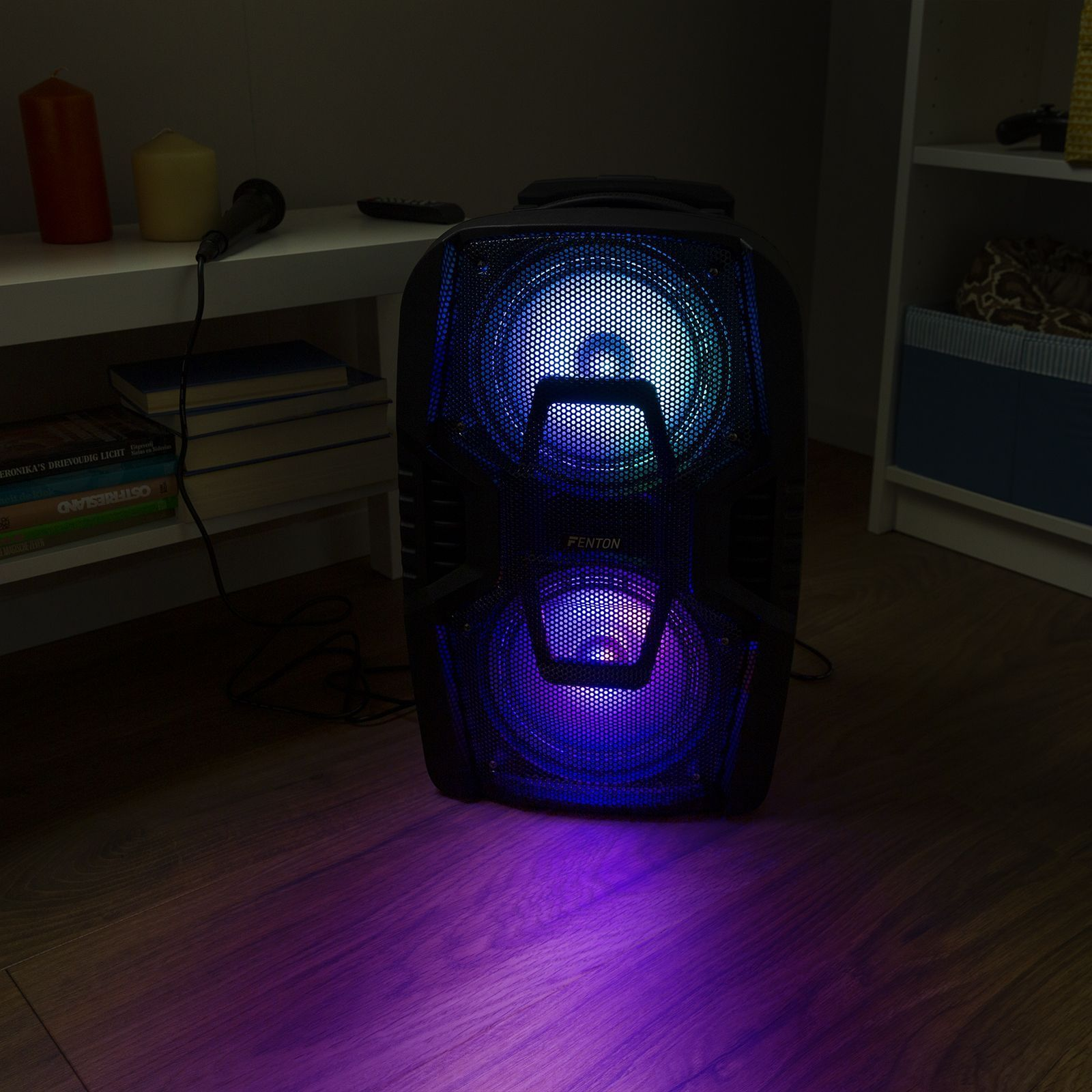 Zwarte luidspreker met blauwe en paarse lichten, in een donkere kamer met planken.