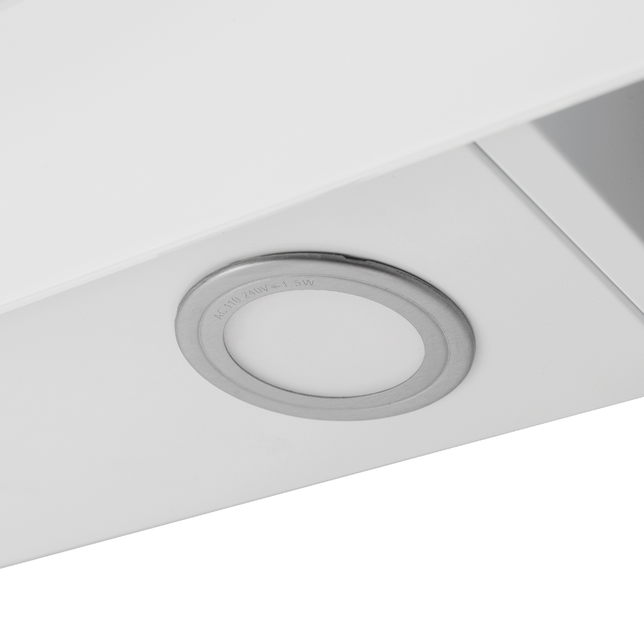Gros plan sur une surface blanche avec un luminaire circulaire à bord argenté.