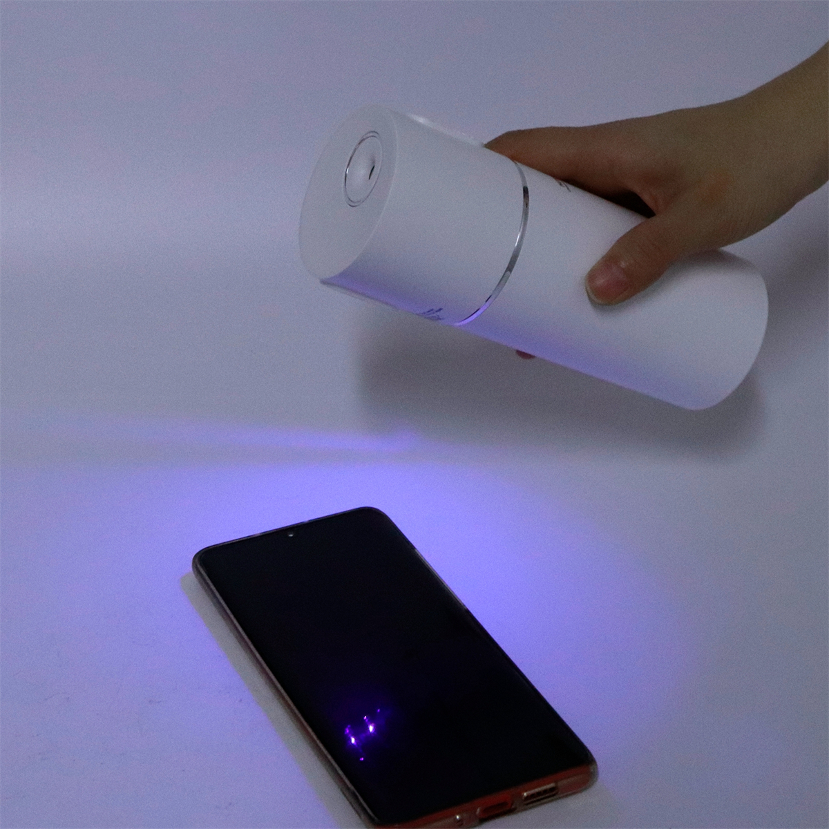 Eine Hand, die Licht auf ein Telefon scheint, möglicherweise zur Desinfektion.