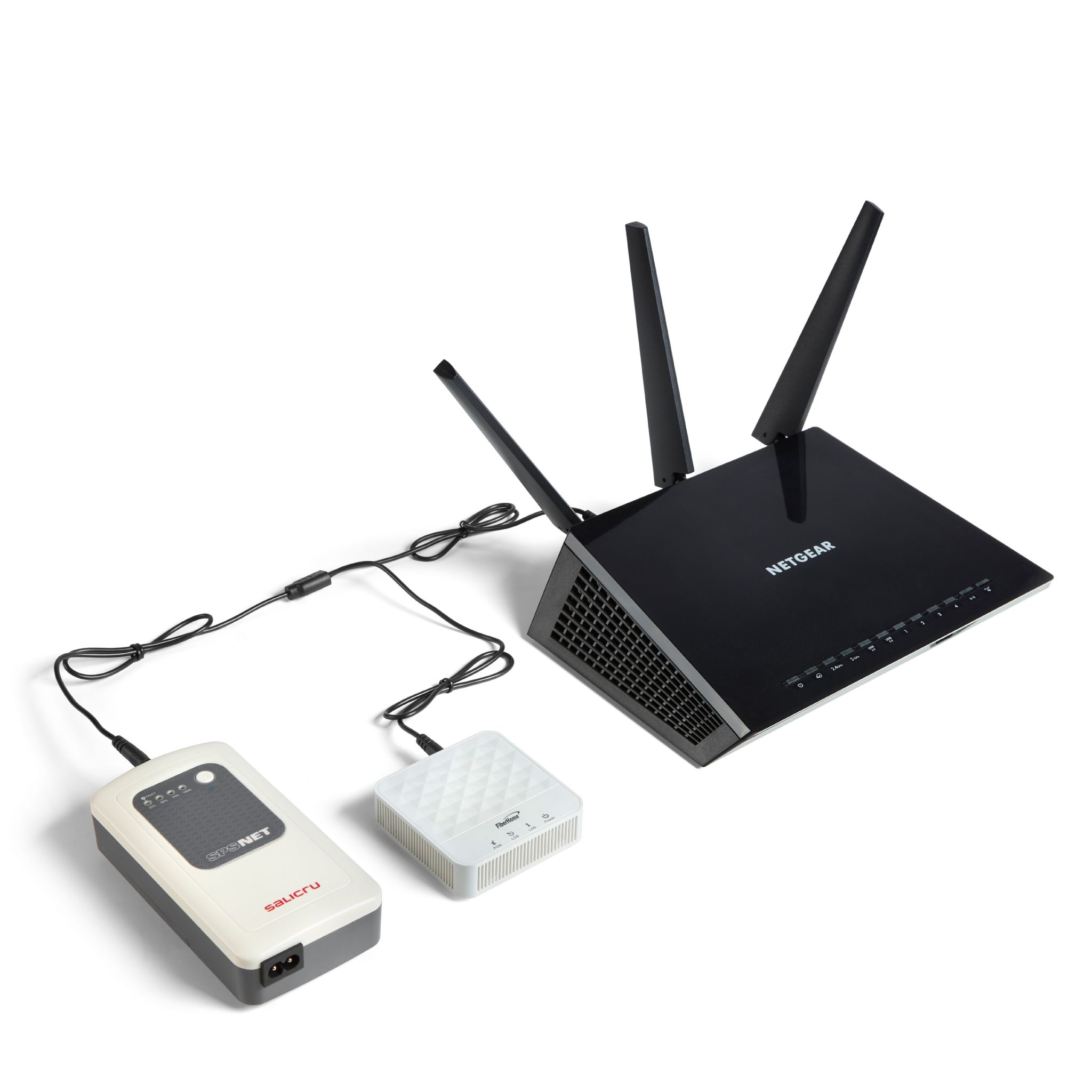 Router NETGEAR negro con antenas, conectado a dos dispositivos blancos y grises.
