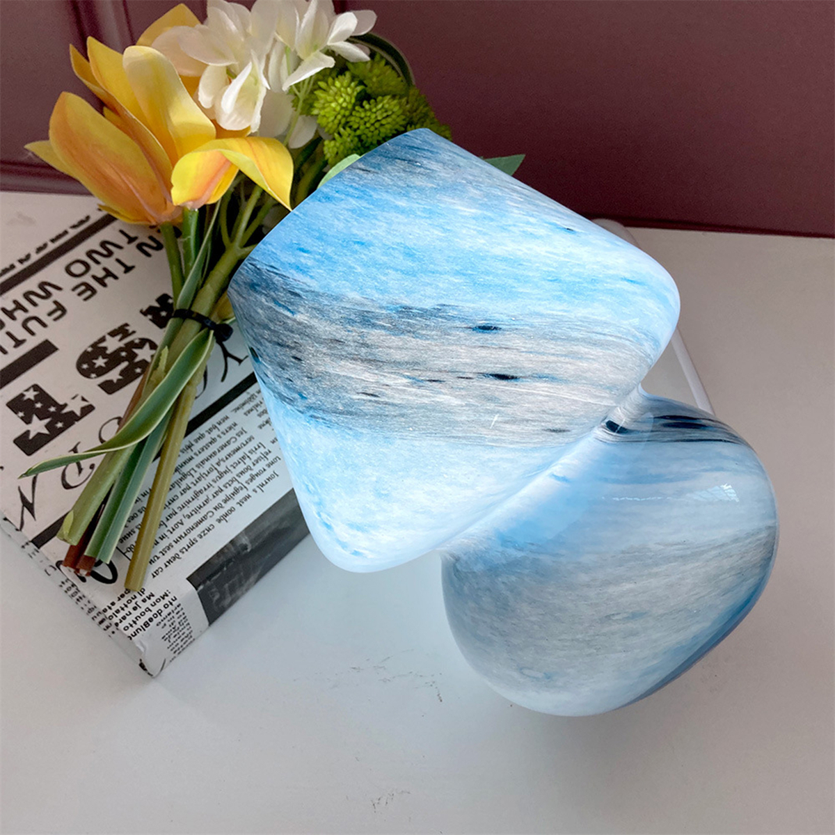 Blau-weiß gewirbelte Glasbecher mit Blumenstrauß.