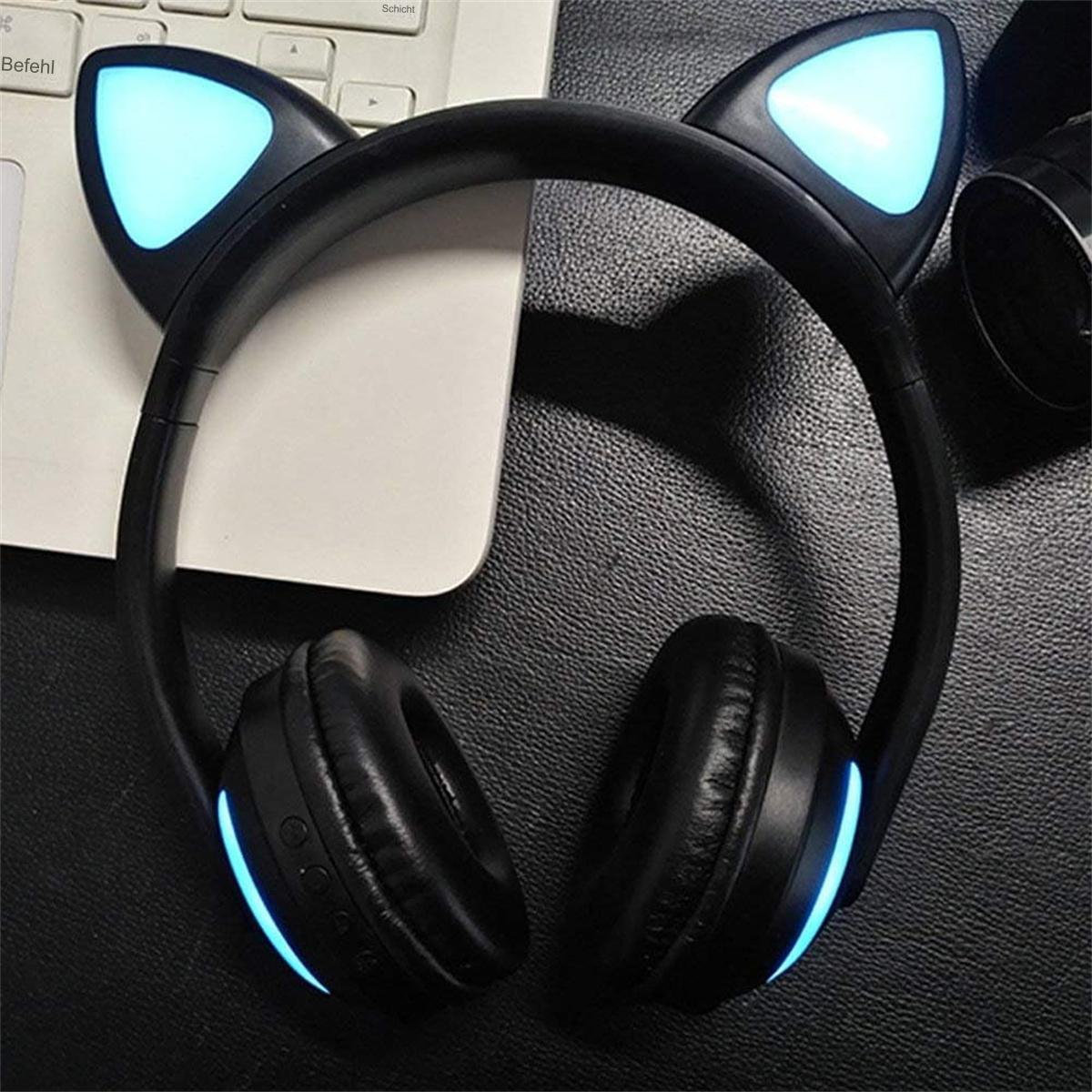 Schwarze Katzenohrkopfhörer mit blau leuchtenden Lichtern auf einem Tisch, in der Nähe einer Tastatur.