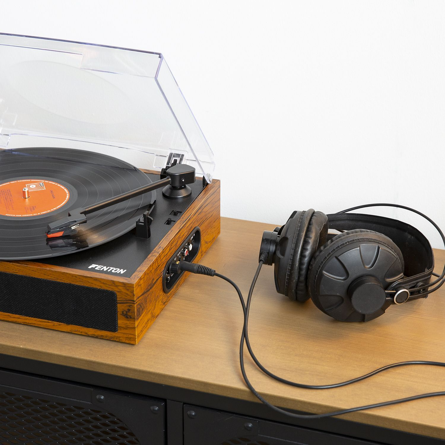 Turntable and headphones on a table. Wooden turntable with headphones plugged in, in a room.