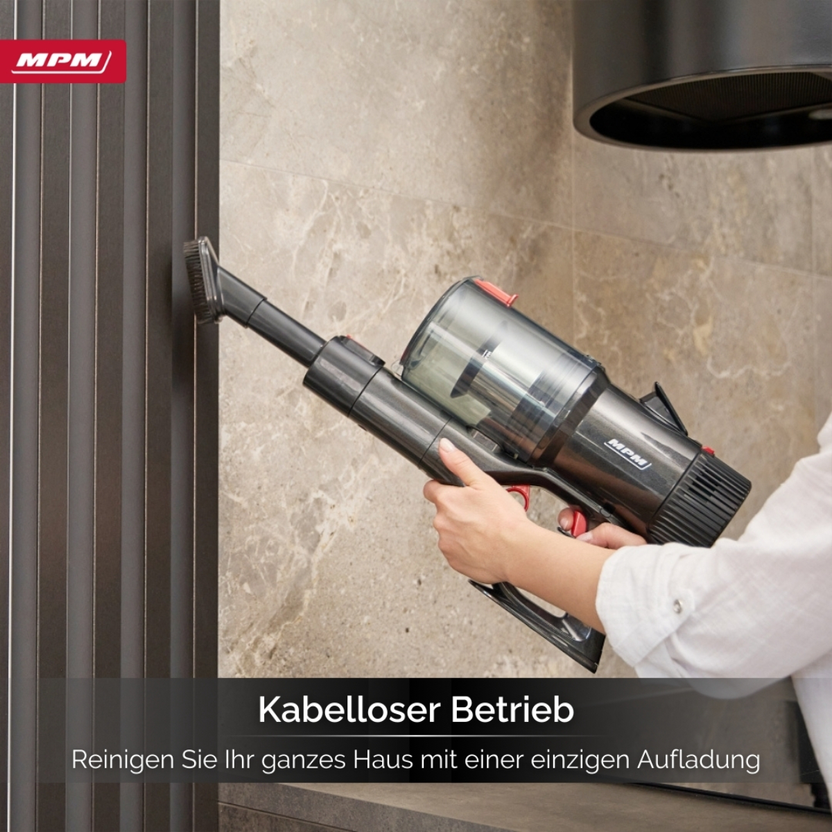 Eine Person, die einen kabellosen Staubsauger benutzt. Der Staubsauger wird an einer Wand verwendet.