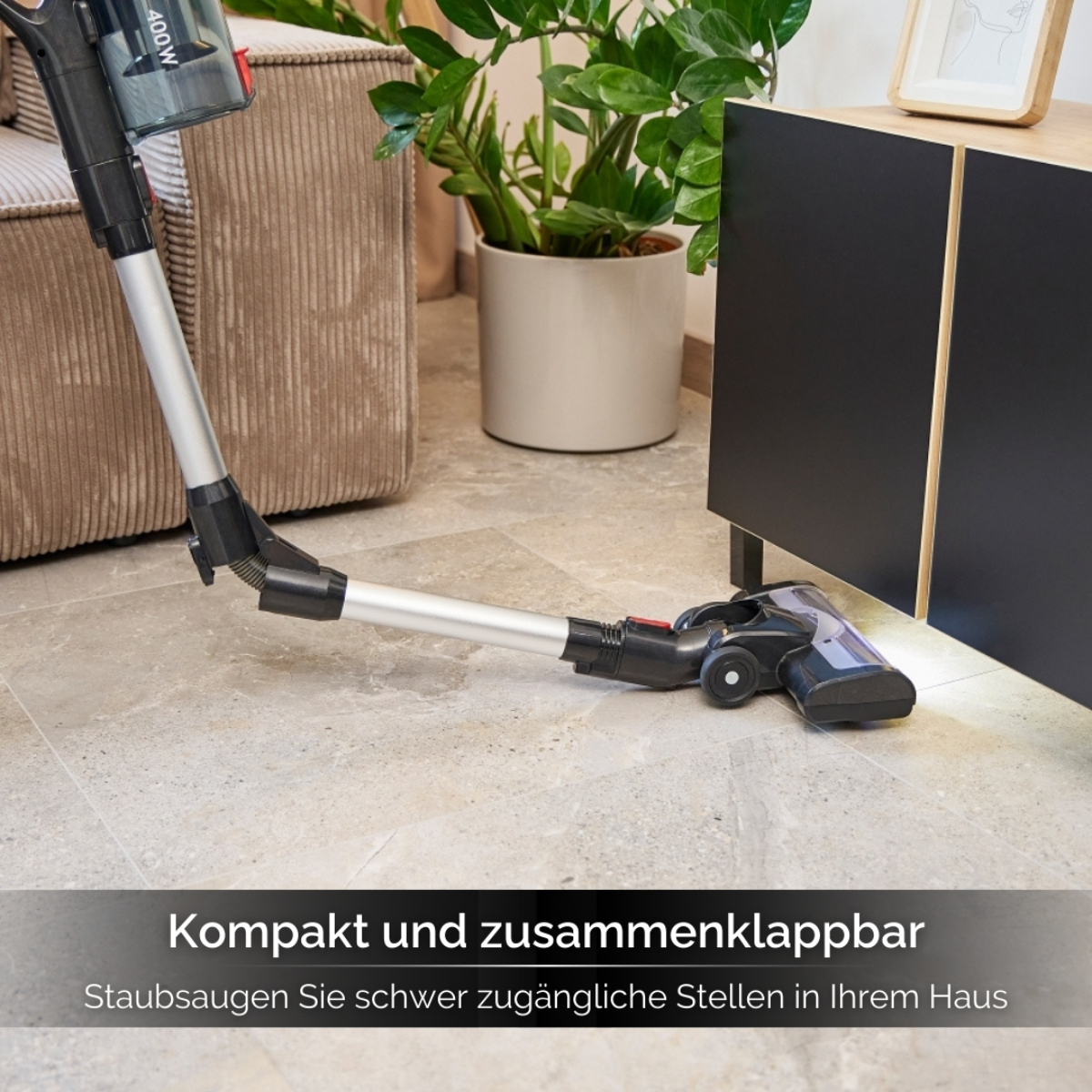 Ein Staubsaugerkopf auf grauem Boden, mit einem dunklen Schrank und einem Blumentopf im Hintergrund.