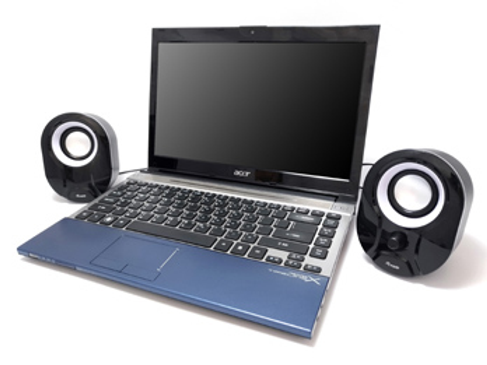 Un laptop con schermo nero e tastiera blu, insieme a due altoparlanti neri su una superficie bianca.