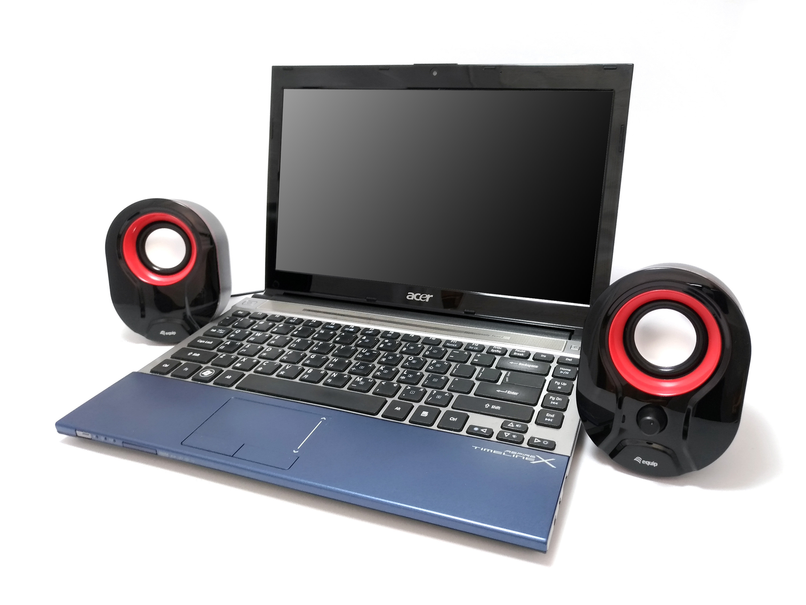 Laptop con altoparlanti su superficie bianca. Laptop aperto, altoparlanti neri e rossi.