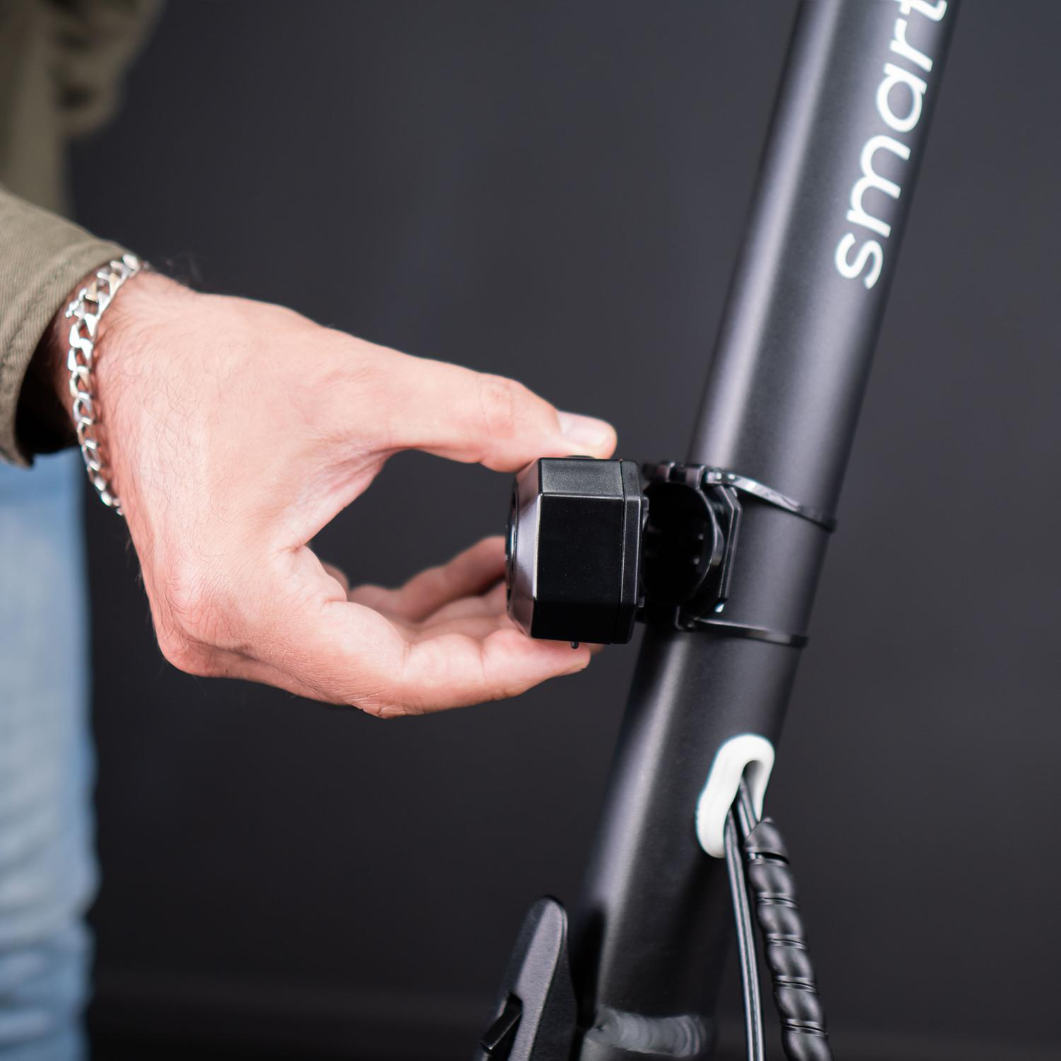 Ręka regulująca czarne światło na czarnym słupku skutera. Skuter ma biały tekst smart.