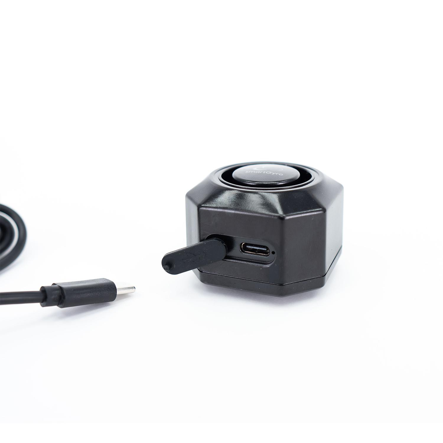 Czarny, ośmiokątny sprzęt z portem USB-C i kablem. Białe tło.