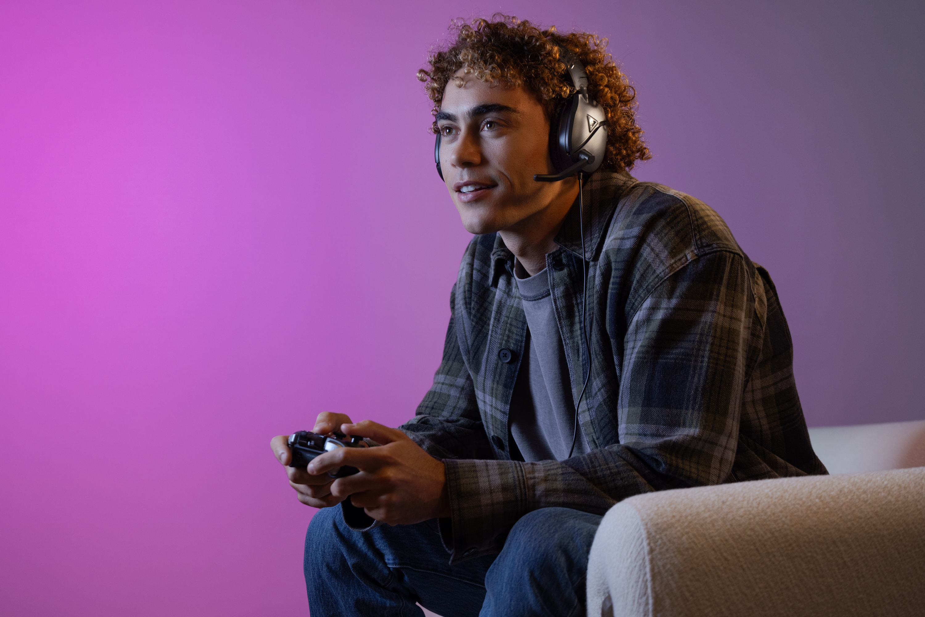 Mężczyzna gra w grę wideo za pomocą kontrolera. Ma na sobie słuchawki do gier.
