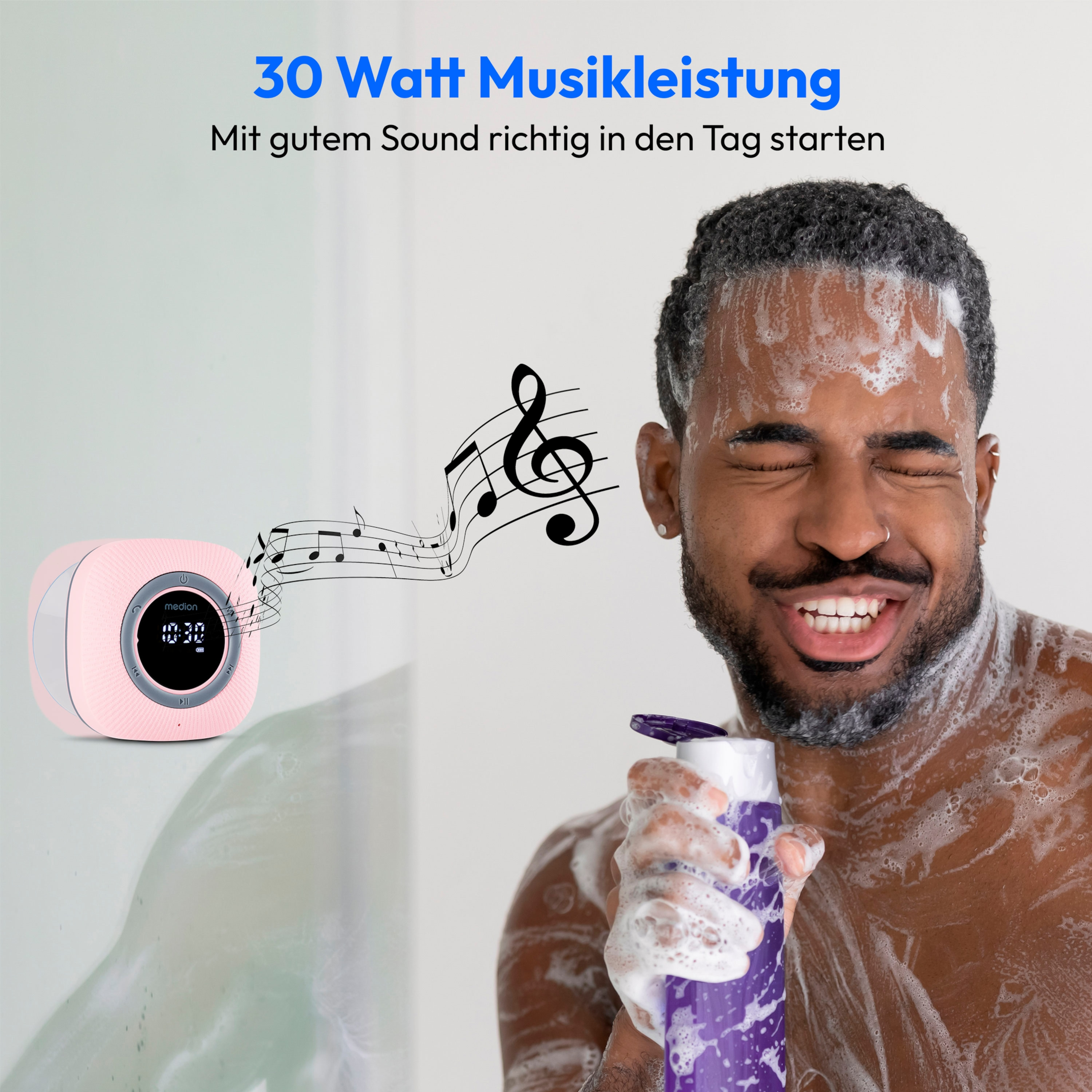 A smiling man is showering. A pink radio is on the counter.