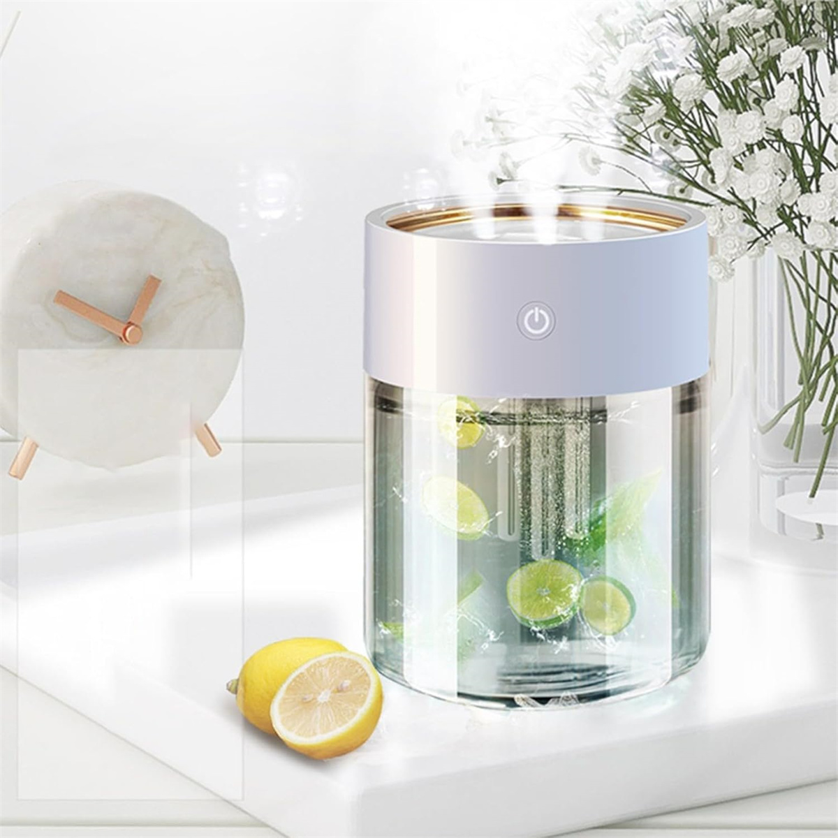 Ein Glasbehälter mit Zitronen und Wasser, eine weiße Uhr und Blumen. Der Behälter steht auf Weiß.