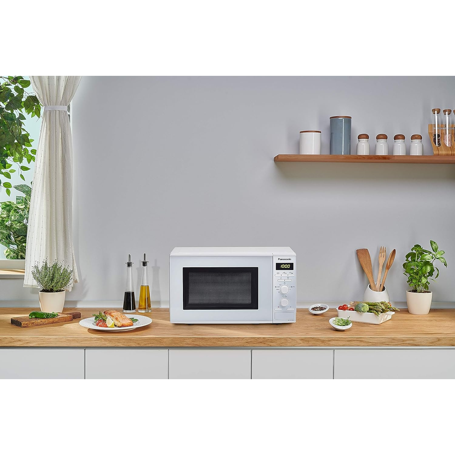 Horno de microondas blanco sobre una encimera de madera con comida y decoraciones.