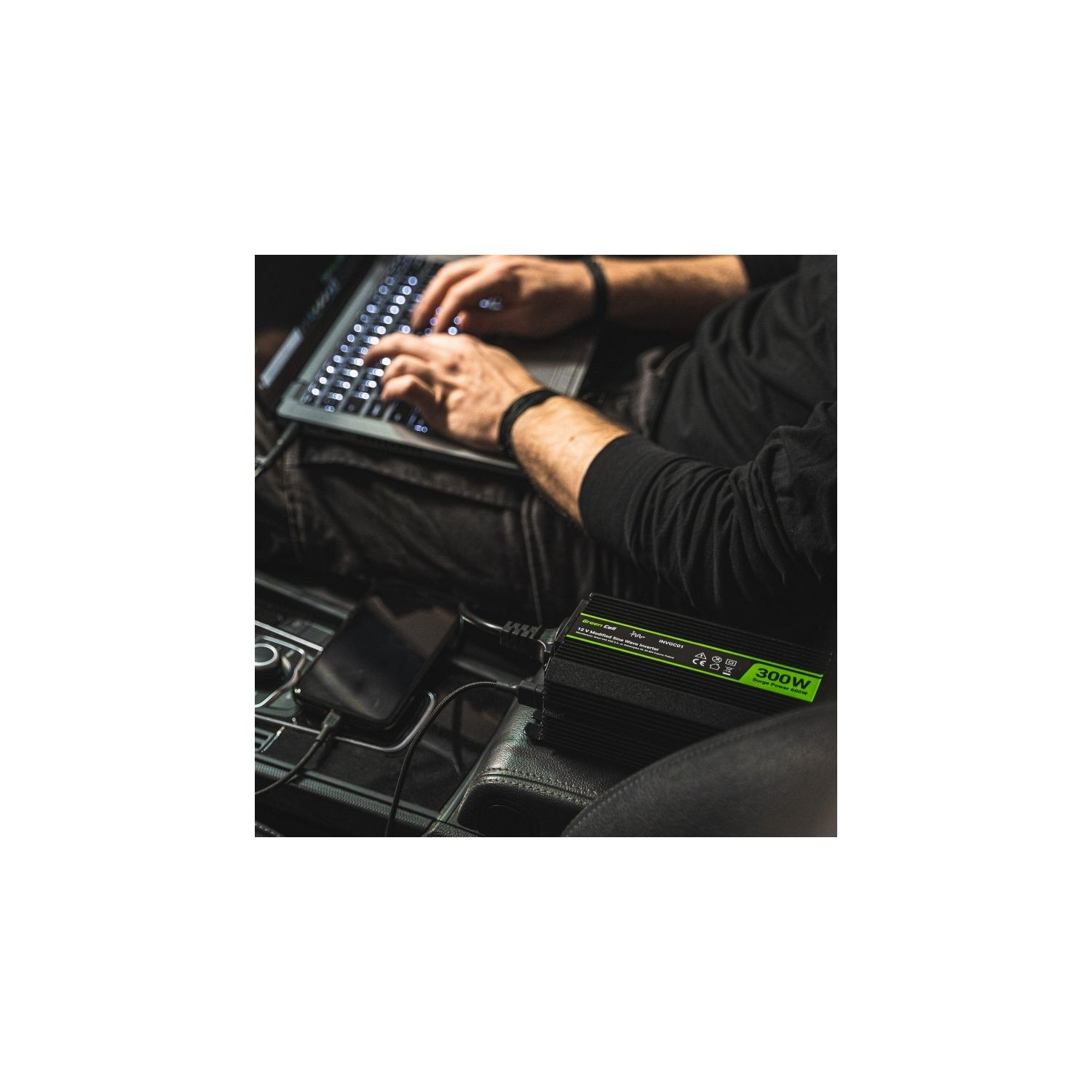 Person arbeitet an einem Laptop, der an einen Wechselrichter im Auto angeschlossen ist.