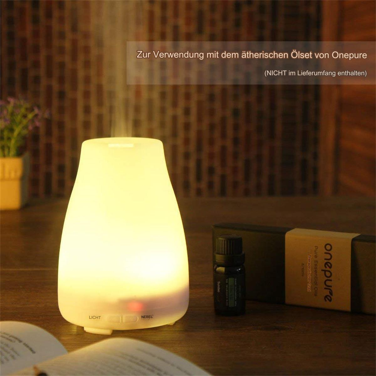 Ein beleuchteter Aroma-Diffusor. Eine kleine Flasche und eine Box daneben. Text auf der Box sichtbar.