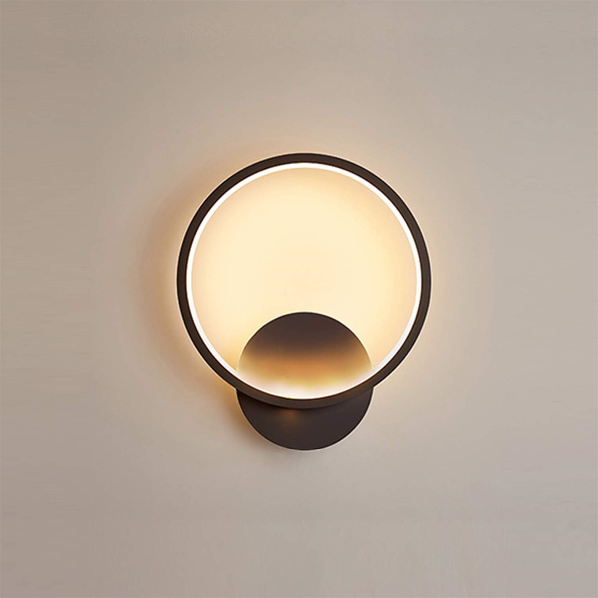 Eine moderne Wandleuchte mit kreisförmigem Design, die warmes Licht ausstrahlt. Darunter ein Halbkreis-Schatten.