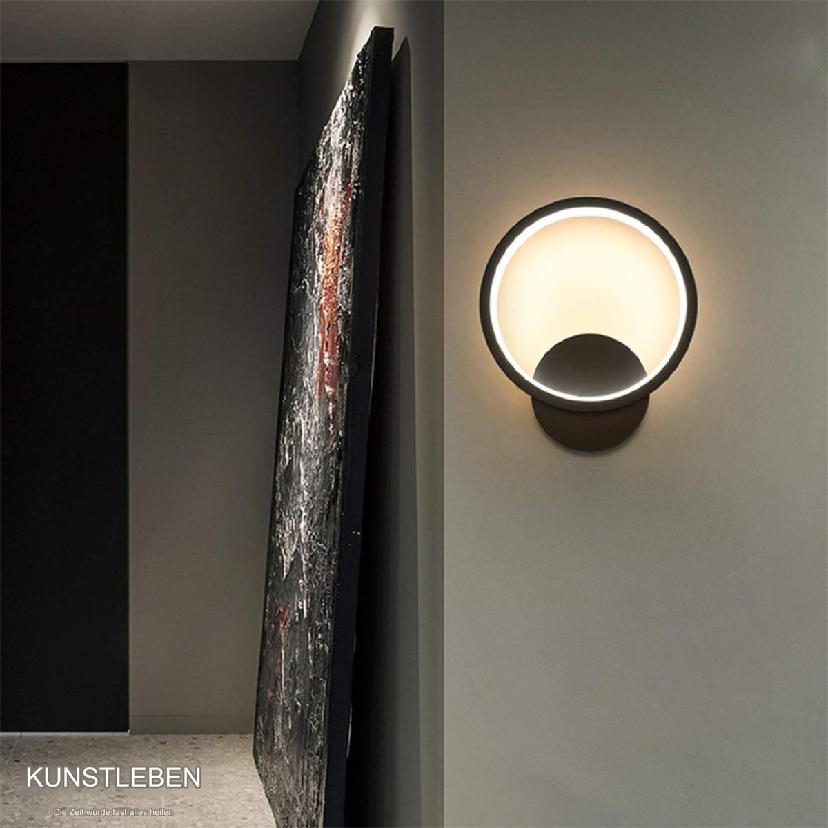 Moderne Wandleuchte mit kreisförmigem Design, die Licht auf eine Wand neben abstrakter Kunst wirft.