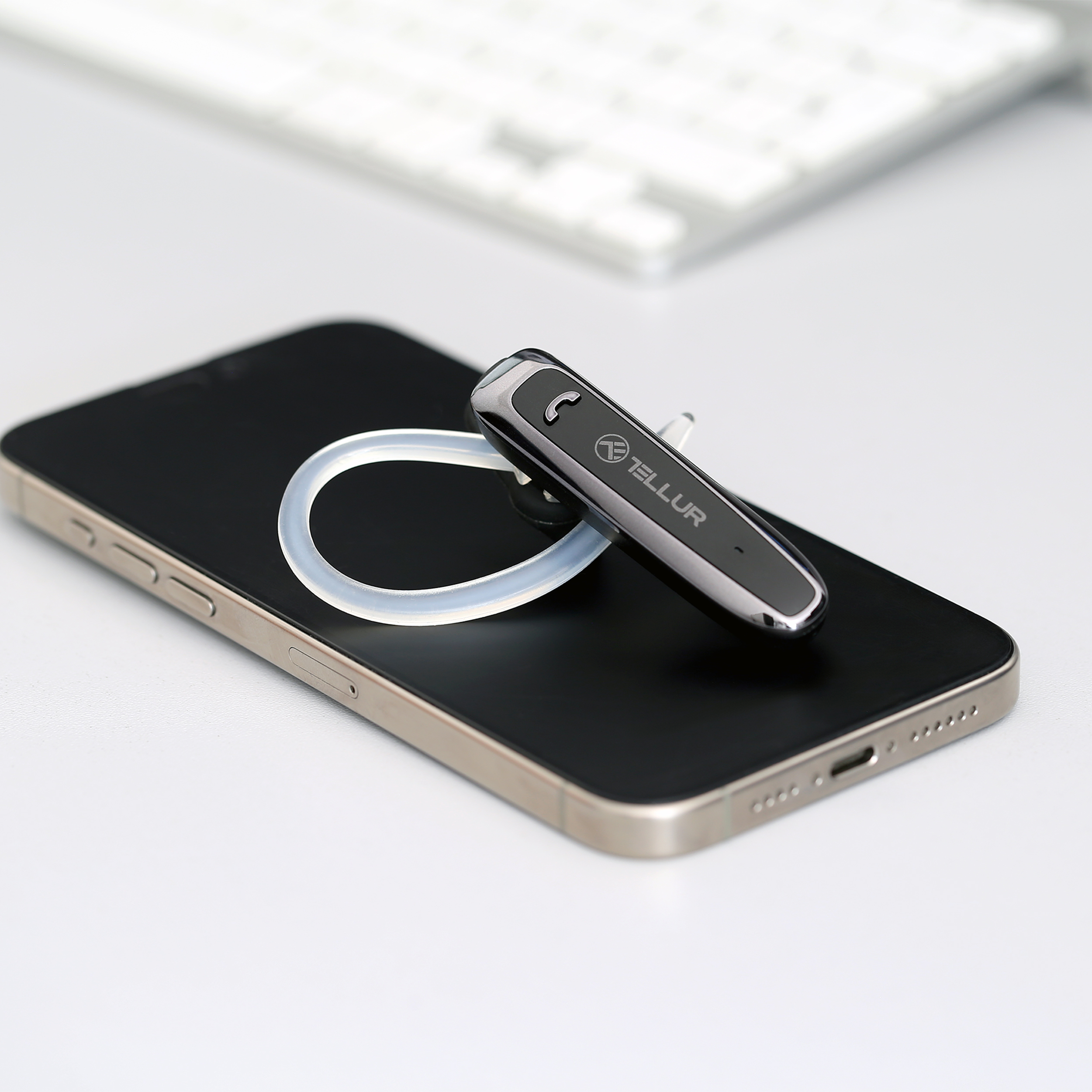 Czarny zestaw słuchawkowy Bluetooth Tellur jest na telefonie. Białe tło.