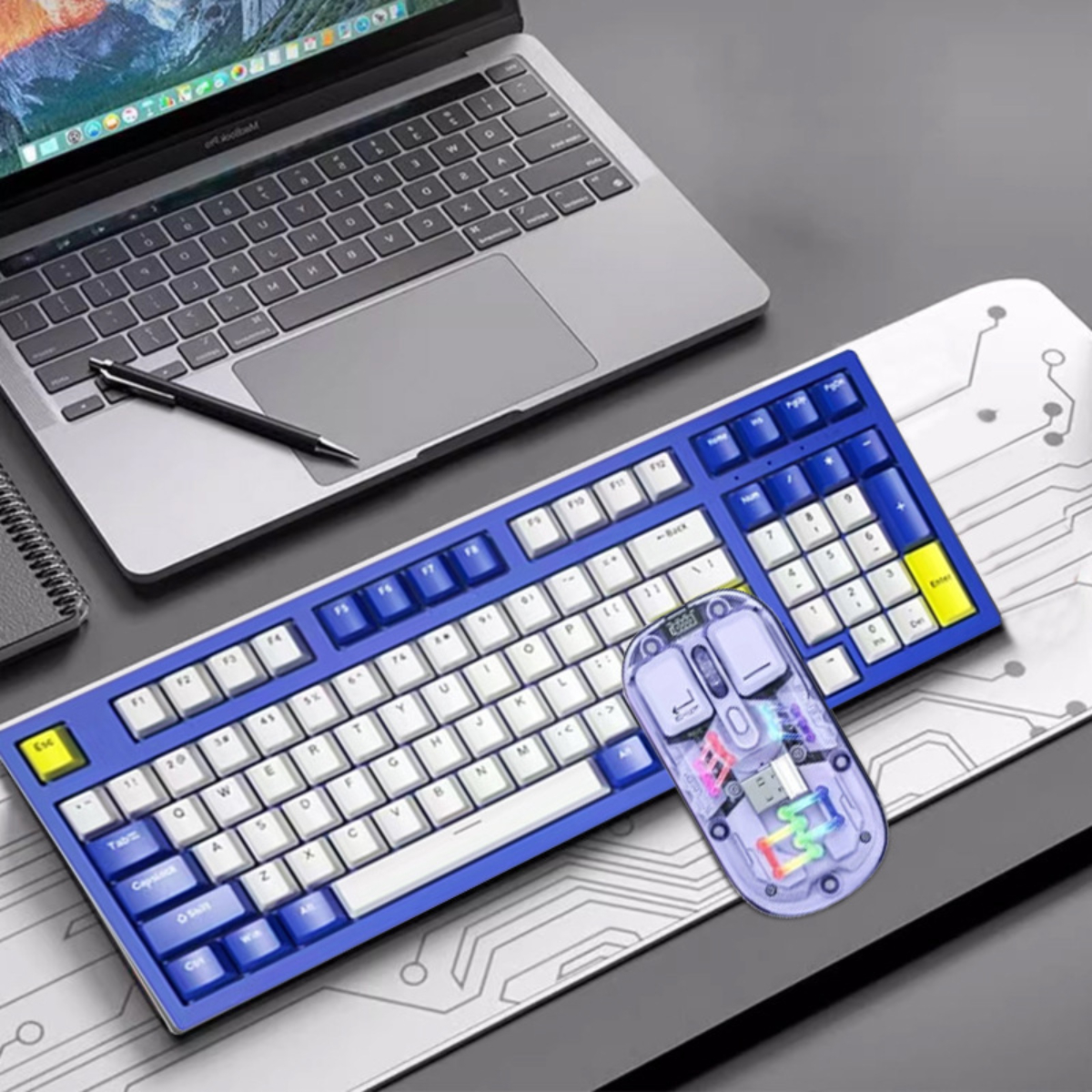 Blau-weißes Tastatur- und Maus-Set auf einem Schreibtisch mit Laptop im Hintergrund.