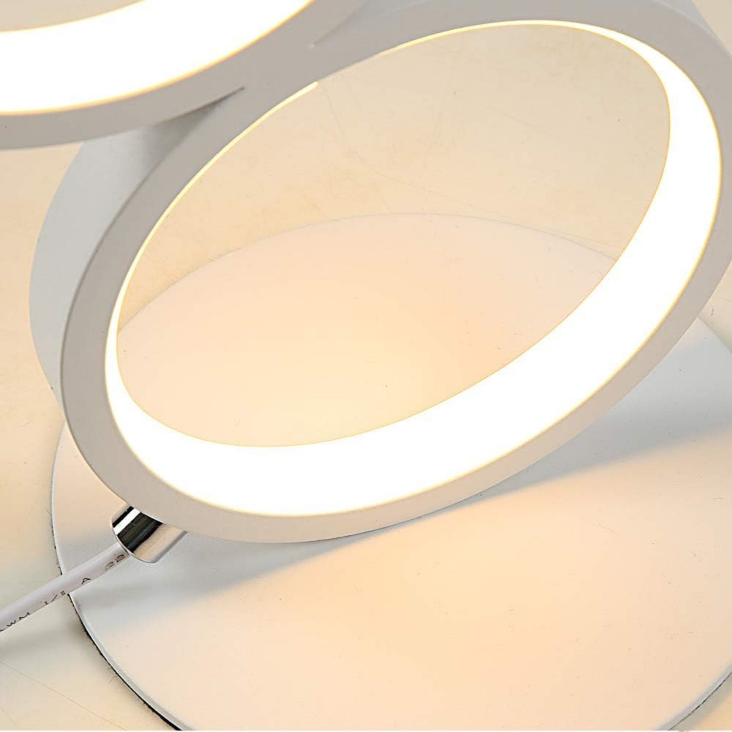 Biała lampa LED o nowoczesnym designie. Dwa kręgi światła są podświetlone.