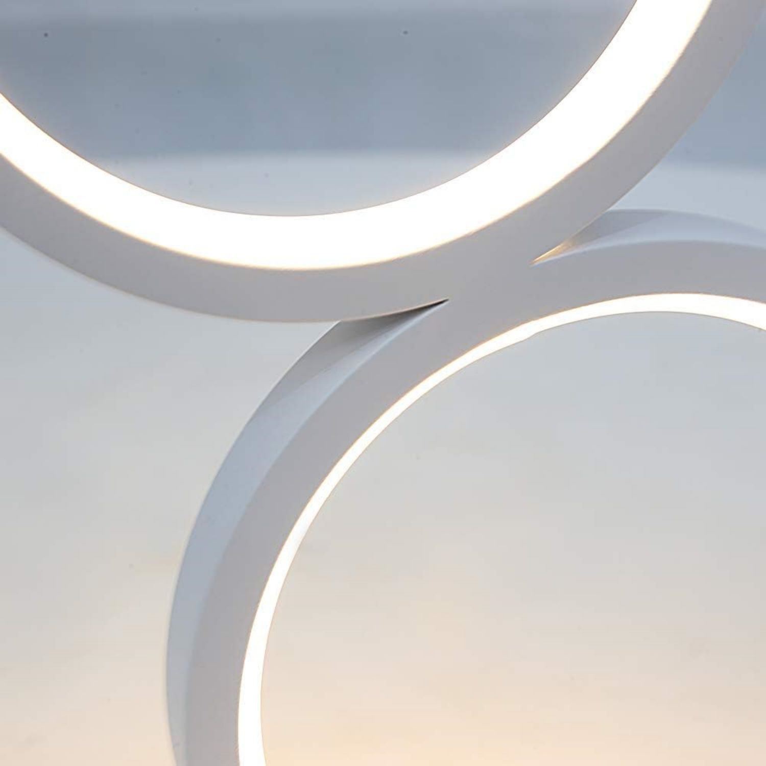 Białe, zakrzywione światła sufitowe LED. Nakładające się pierścienie, emitujące miękki, rozproszony blask.