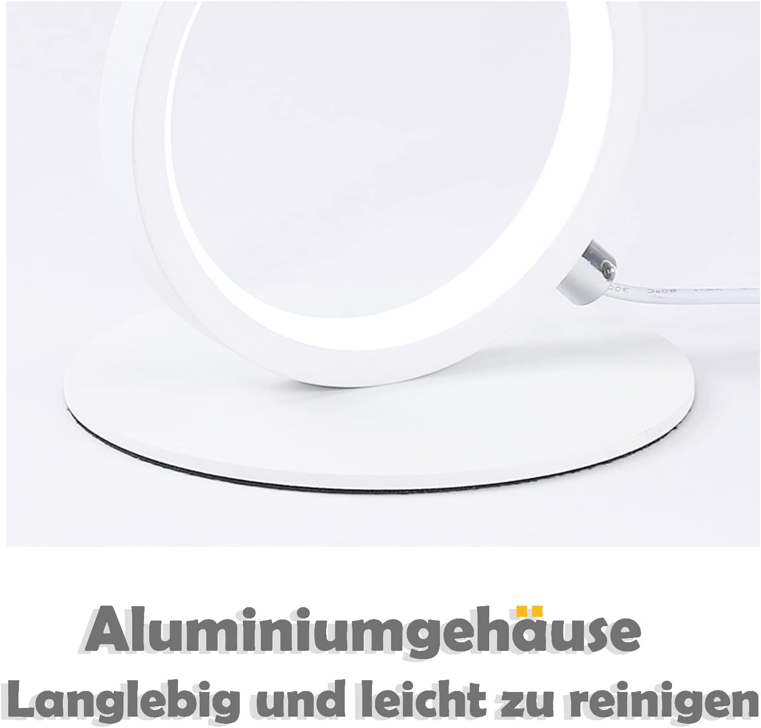 Biała lampa w kształcie pierścienia na białej podstawie. Tekst: 'Obudowa aluminiowa, trwała i łatwa w czyszczeniu'.