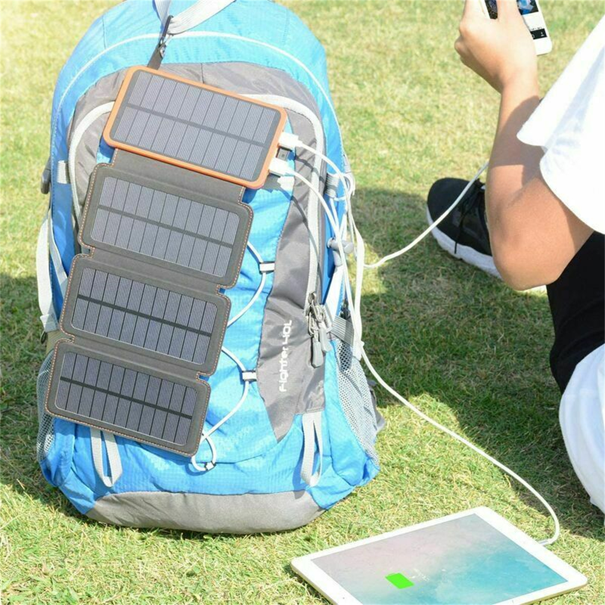 Eine Person benutzt einen blauen Rucksack mit Solarpanel, um ein Tablet aufzuladen.