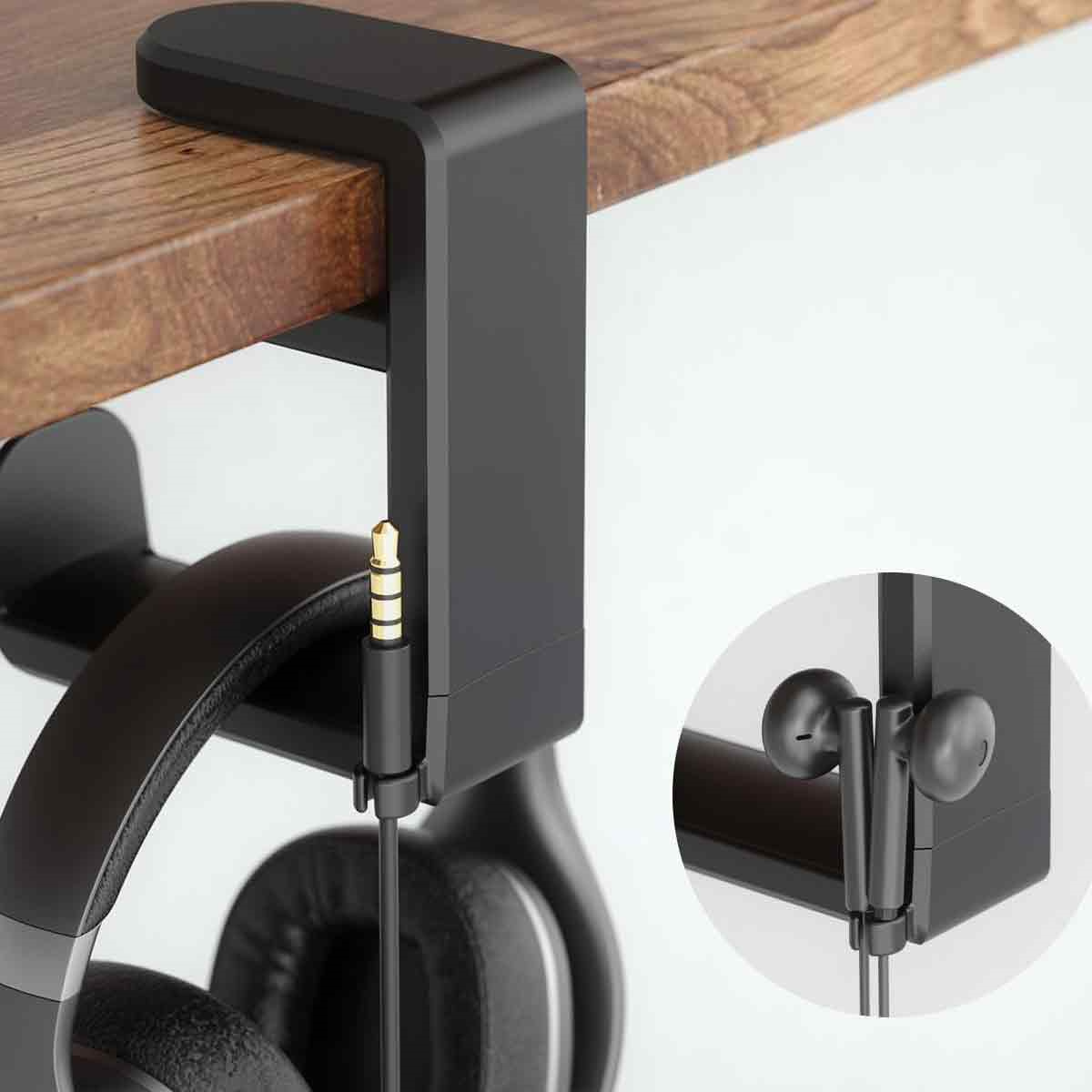 Schwarzer Kopfhörerhalter an einer Holzoberfläche befestigt.  In-Ear-Kopfhörer hängen darunter.