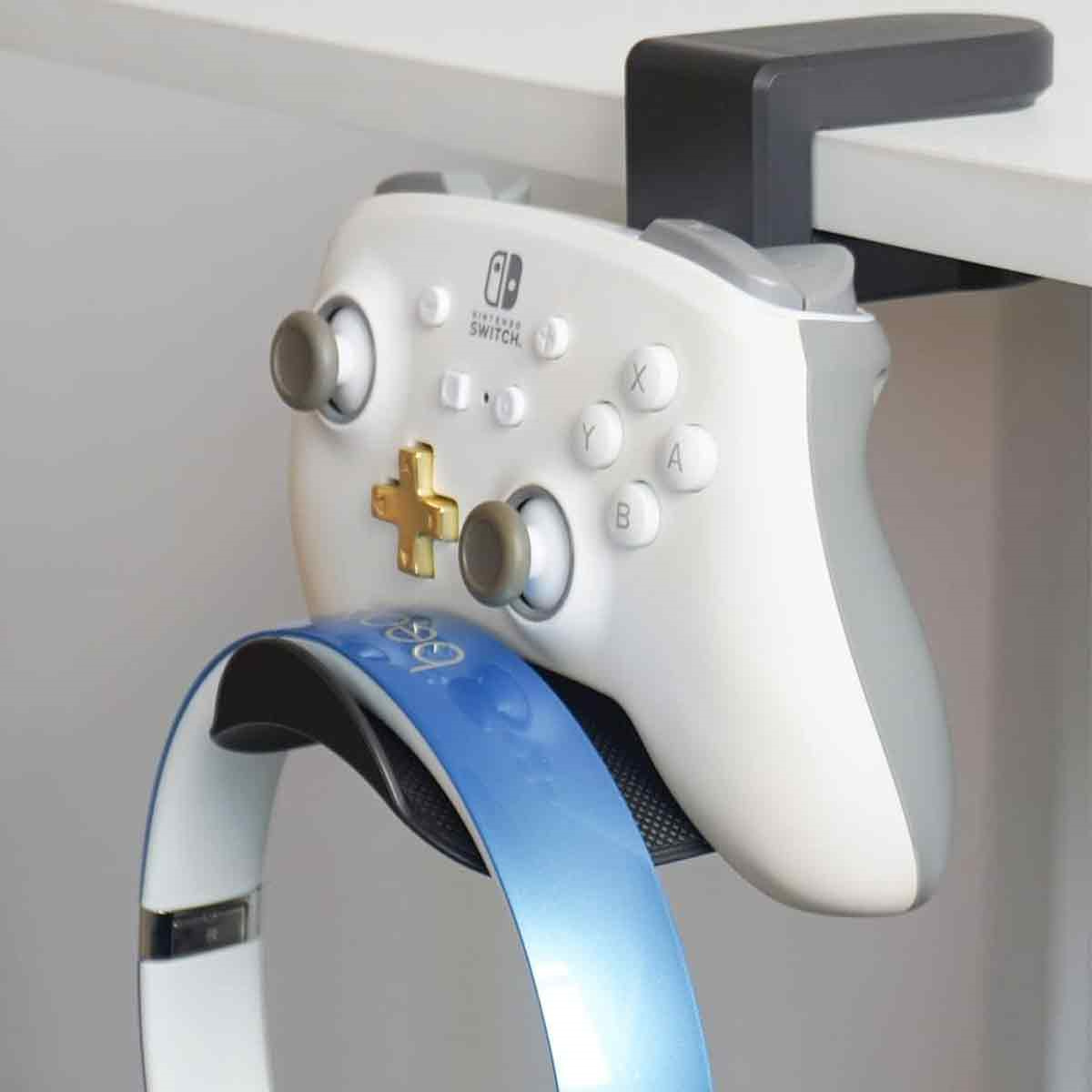 Ein weiß-grauer Nintendo Switch Controller hängt an einem Schreibtisch. Ein blaues Headset ist ebenfalls sichtbar.