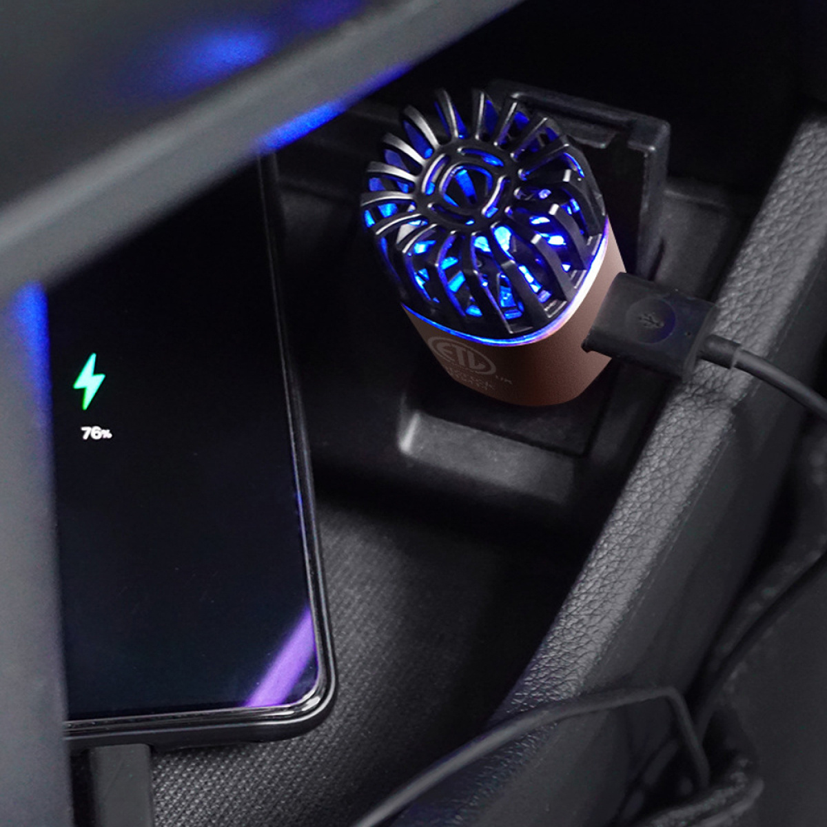 Auto-Innenraum mit ladendem Telefon und Lufterfrischer mit blauem Licht.