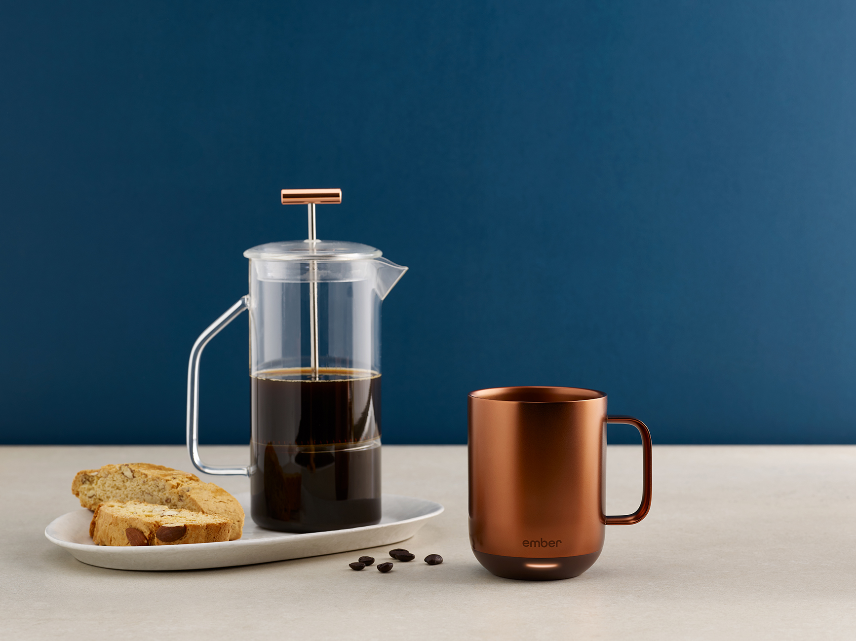 Preparazione del caffè: caffettiera francese con caffè, tazza di rame e biscotti su un piatto bianco.