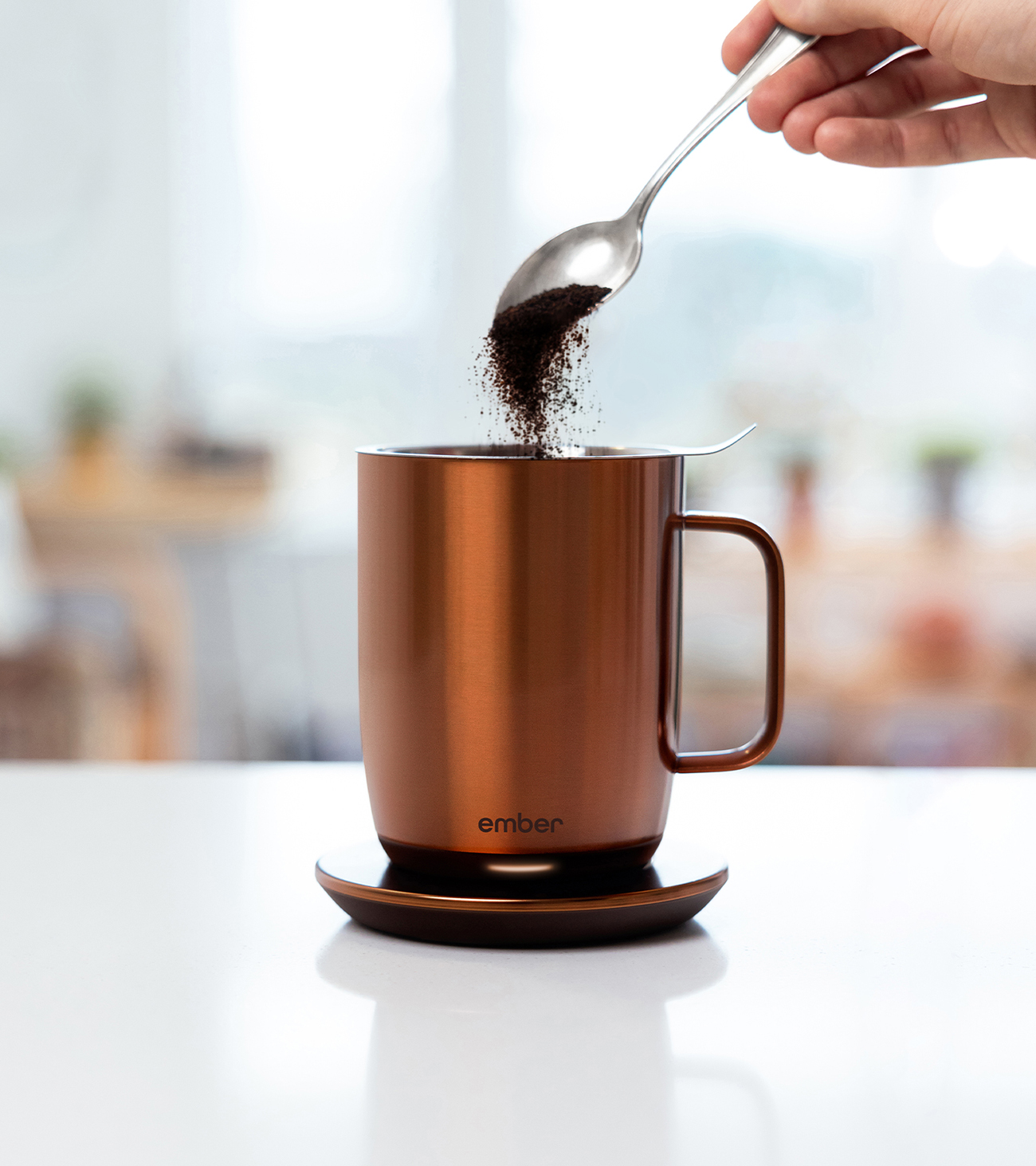 Fondamento di caffè versato in una tazza di rame su una base riscaldante. Cucchiaio sopra.