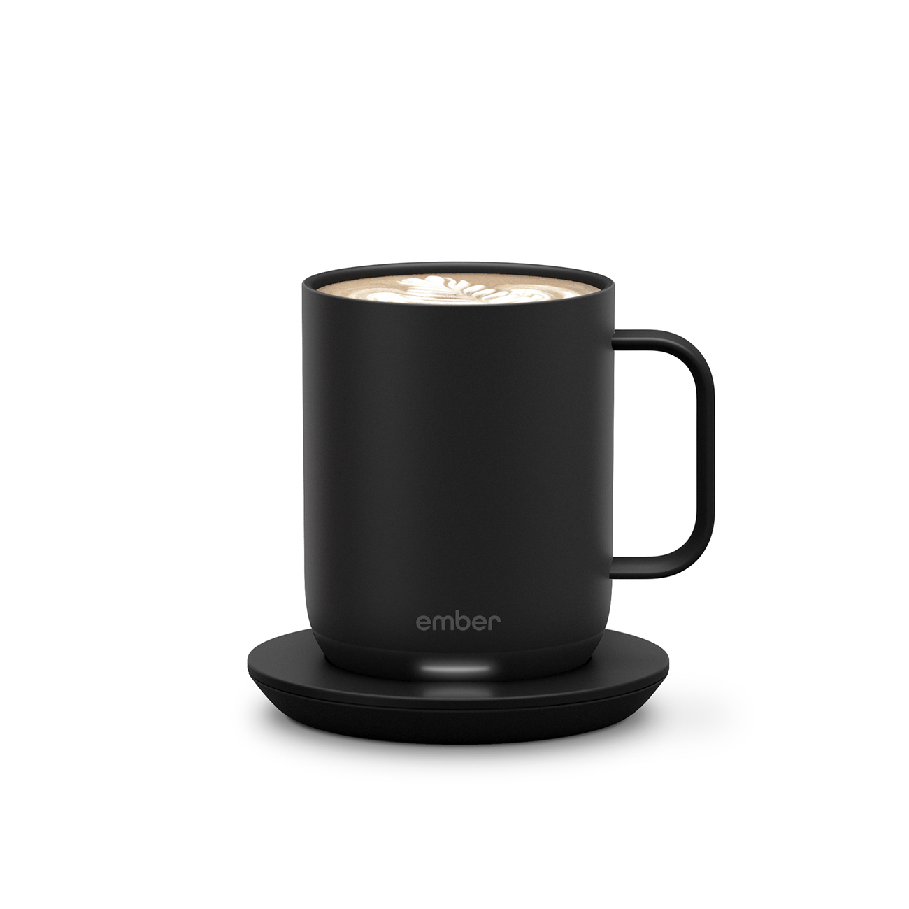 Tazza nera con sottobicchiere nero. La tazza ha caffè con schiuma sopra. Lo sfondo è bianco.