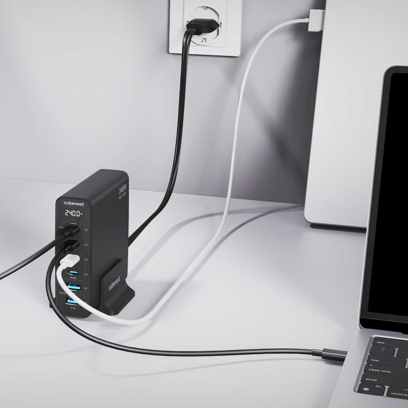 Una stazione di ricarica nera con più porte, collegata a una presa. Si vedono un laptop e dei cavi.