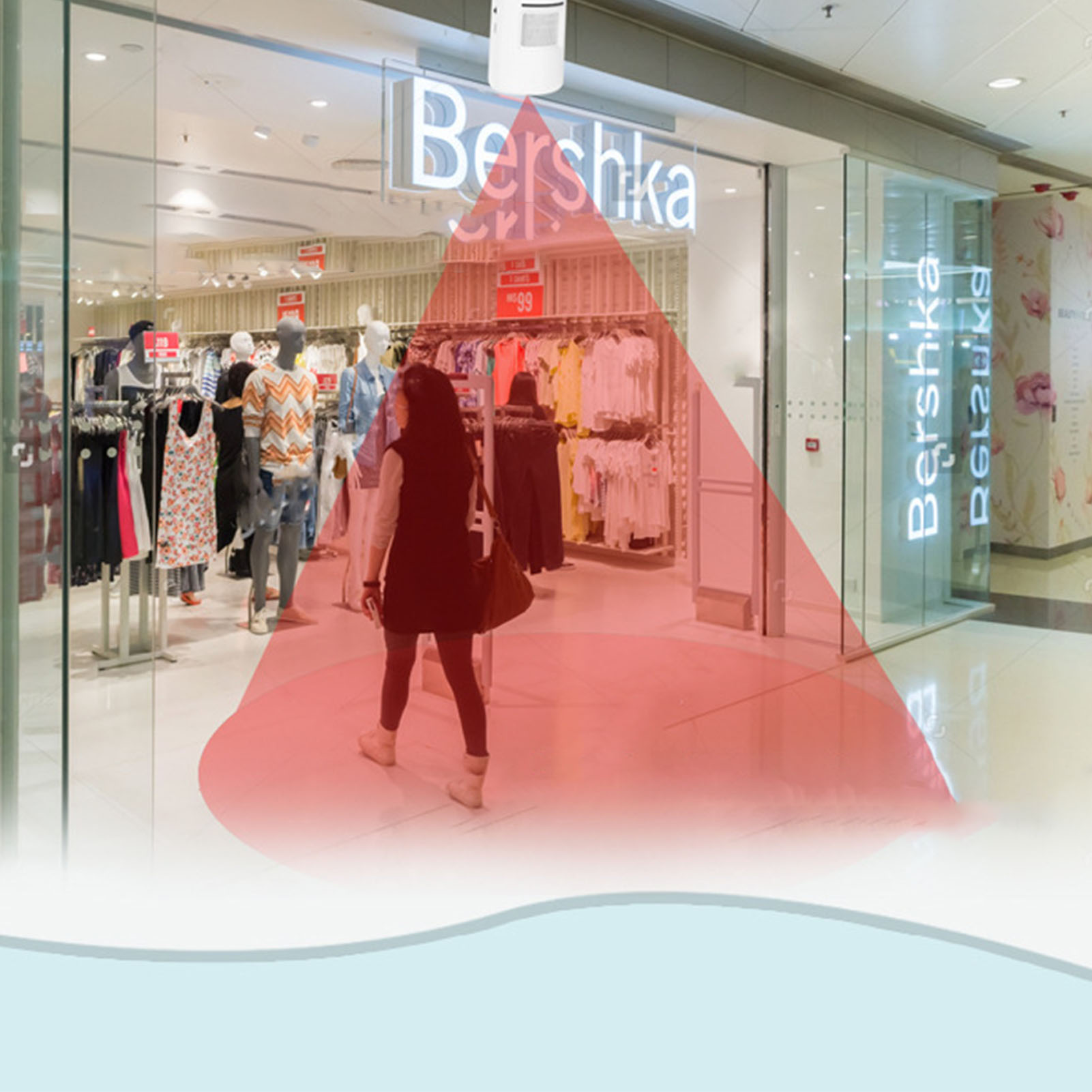 Frau geht in einem Einkaufszentrum auf das Geschäft Bershka zu. Rotes Sicherheitslicht wird gezeigt. Hintergrund ist das Innere des Einkaufszentrums.