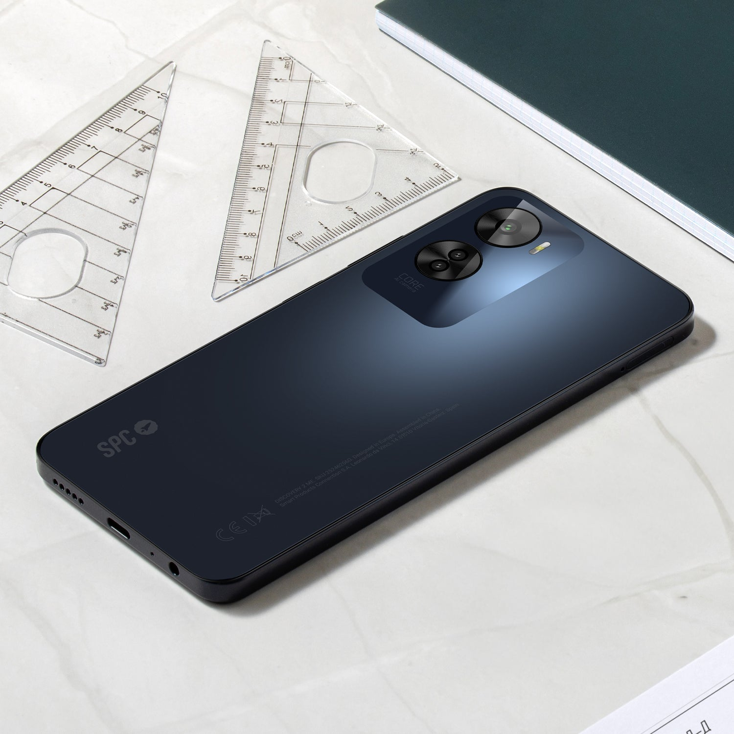 Ein schwarzes Telefon mit Kamera, das auf einer Oberfläche mit Linealen liegt.