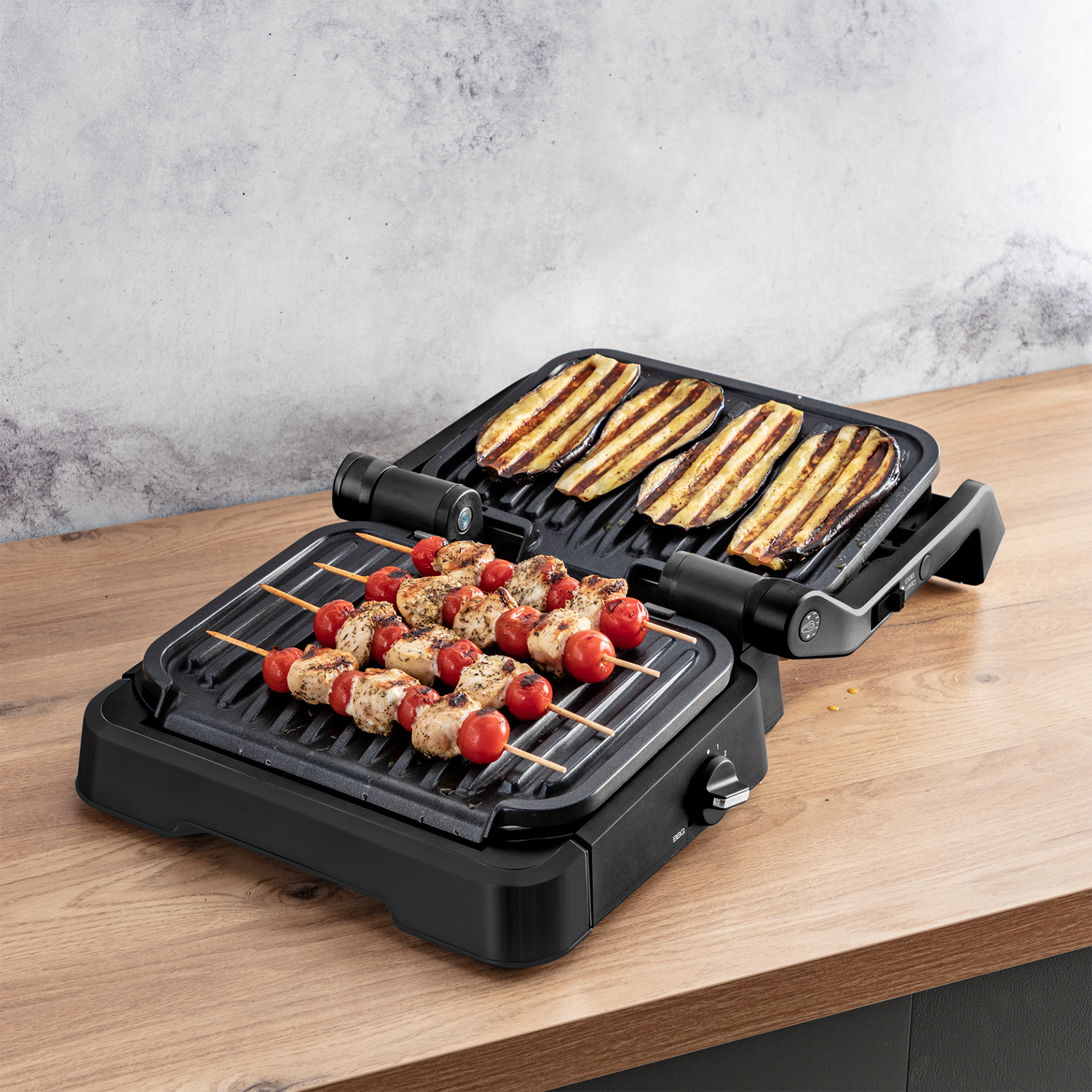 Grill z szaszłykami z pomidorów i kurczaka oraz plastrami bakłażana. Czarny grill na drewnianej powierzchni. Urządzenie kuchenne.
