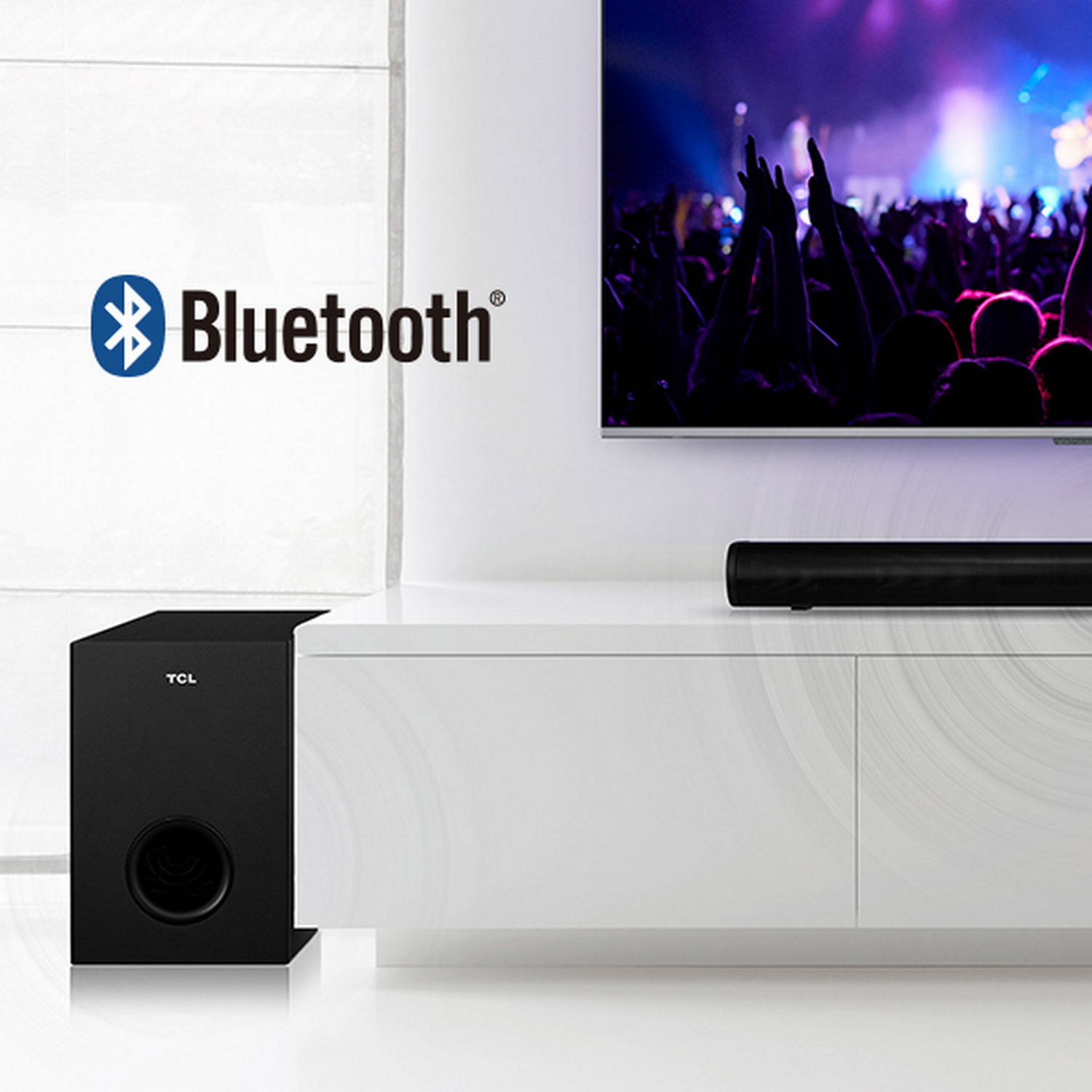 Configurazione del soggiorno con un televisore che mostra un concerto. Un subwoofer nero è di fronte.