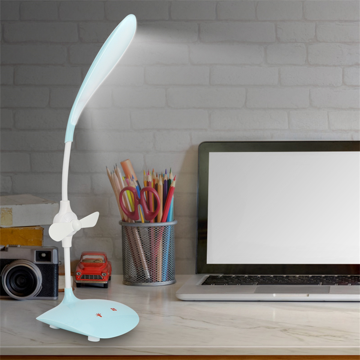 Eine blaue Schreibtischlampe mit Ventilator auf einem Schreibtisch mit anderen Objekten.