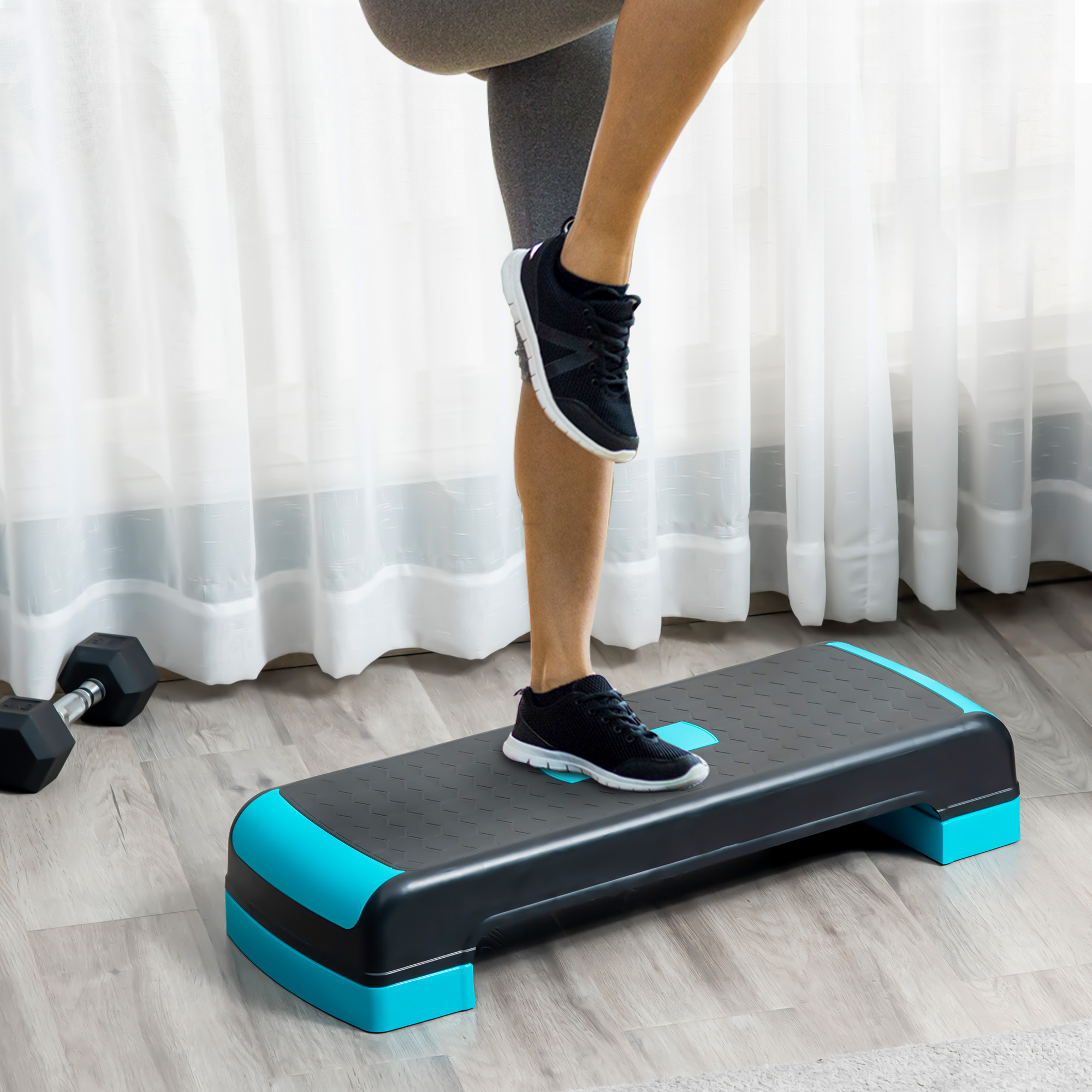 Una persona subiendo a una plataforma de step negra y azul, con pesas.