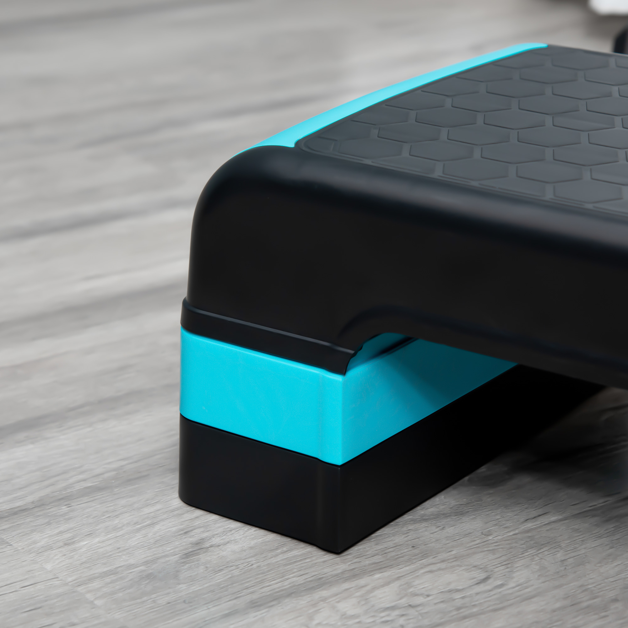 Plataforma de step negra y turquesa sobre un suelo de madera gris claro.
