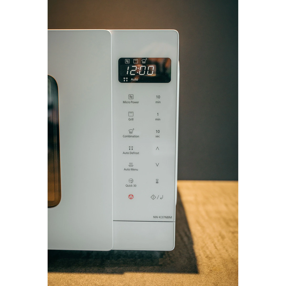 Biała kuchenka mikrofalowa z cyfrowym wyświetlaczem pokazującym godzinę. Widoczny panel sterowania.