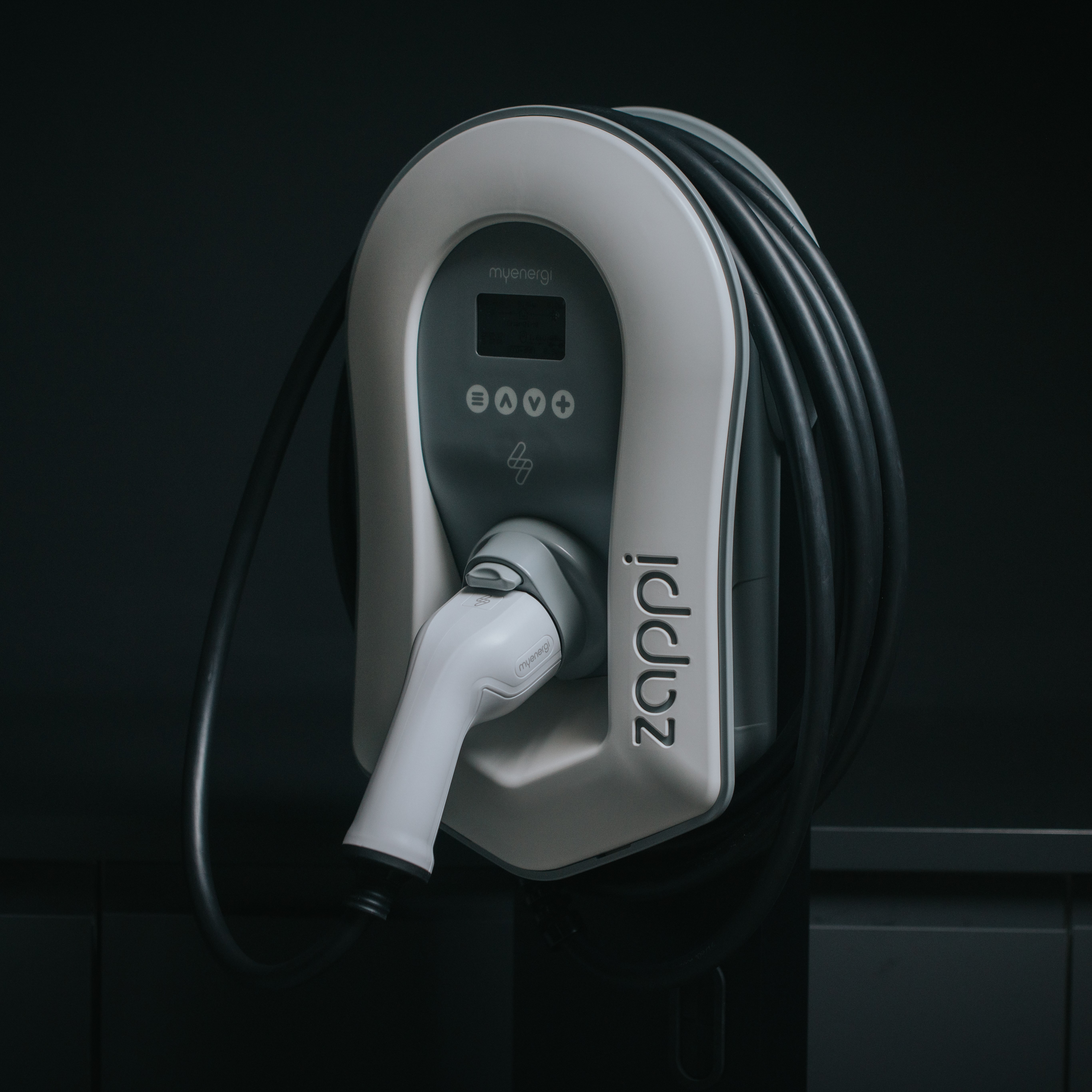 Electric vehicle charger. It's grey and white, with a cable attached. It has a charging port.
