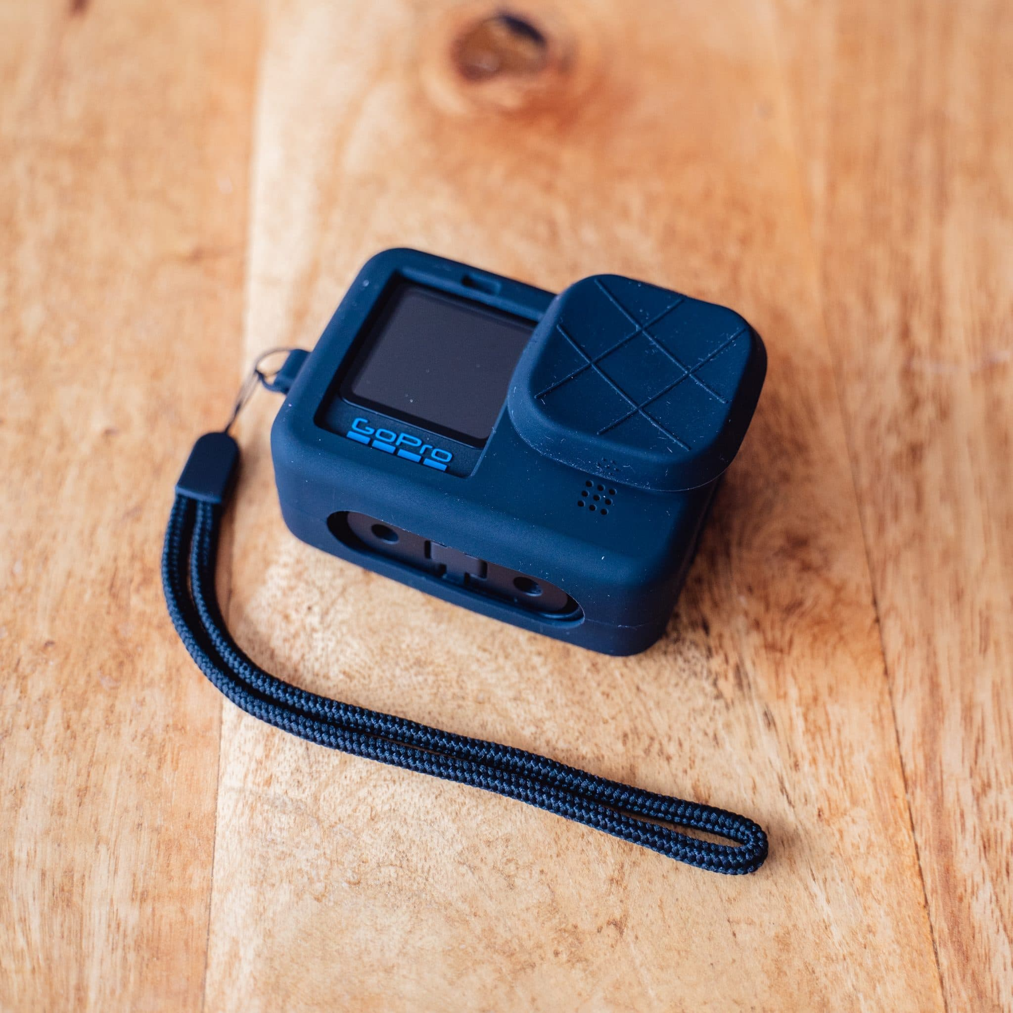 Blauwe GoPro camera met polsband op houten oppervlak.