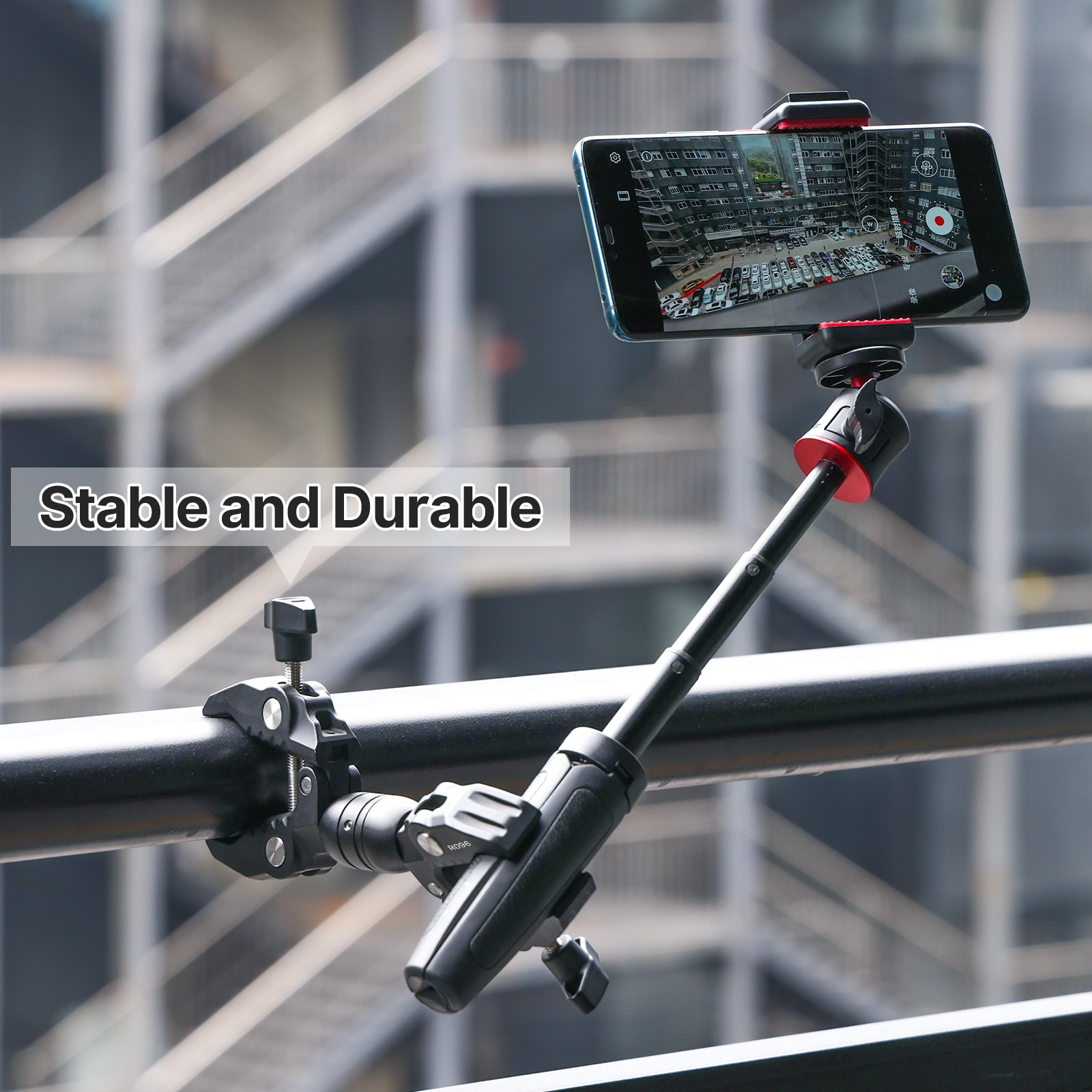Smartphone montato su un treppiede nero su un corrimano, ambiente esterno.