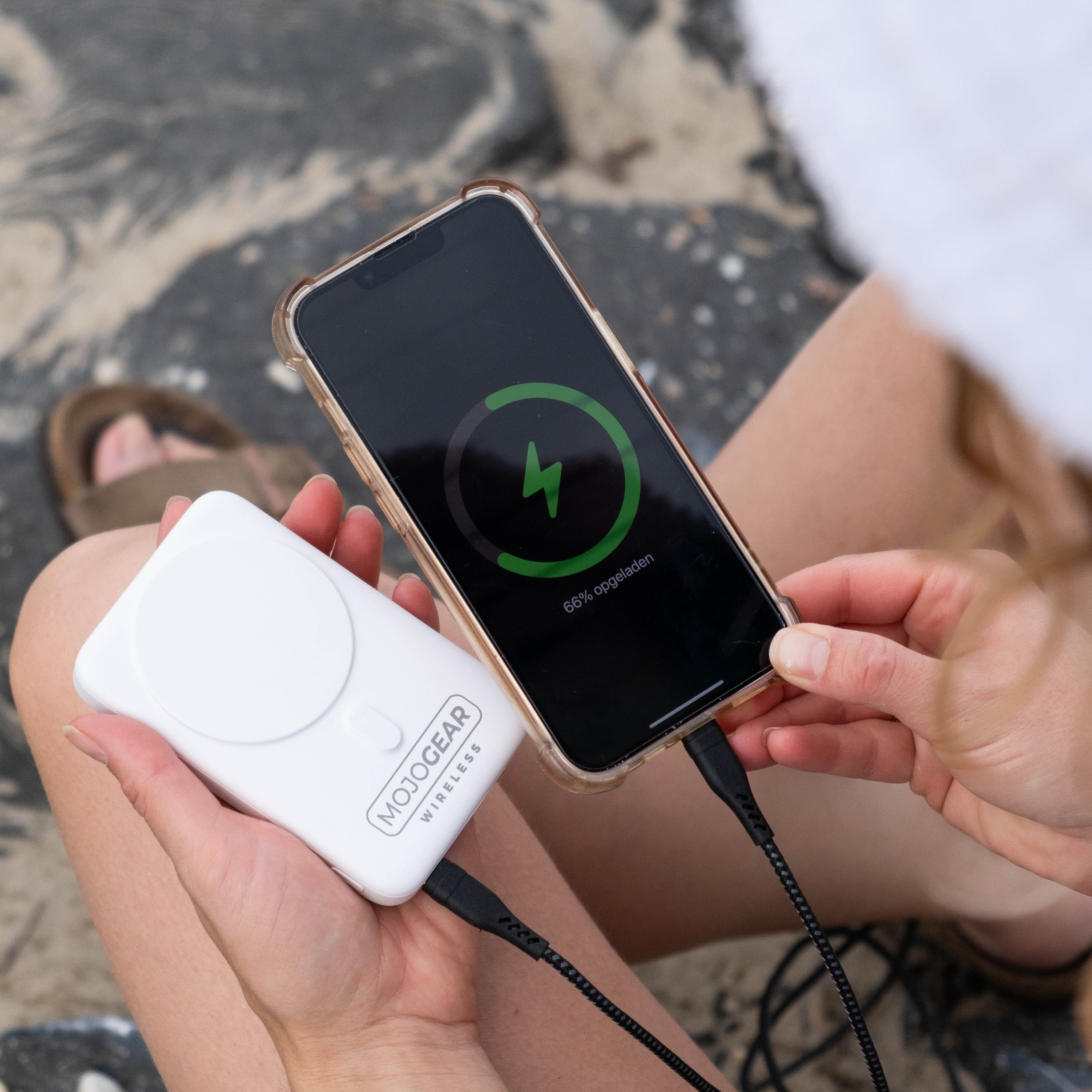 Een telefoon is aangesloten op een witte draagbare oplader. De telefoon geeft de laadstatus weer.