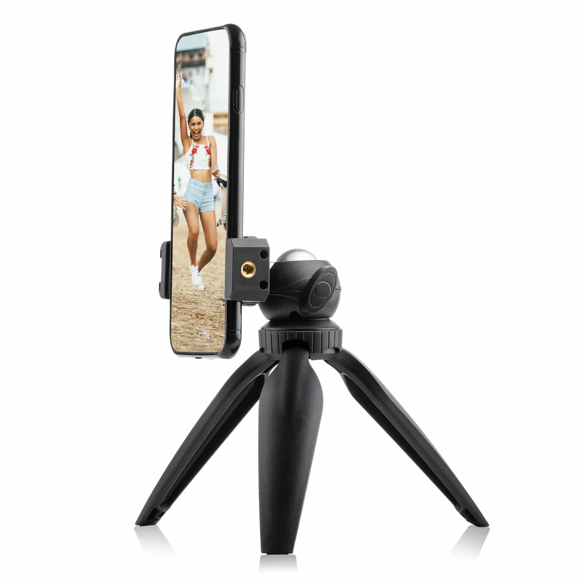A black smartphone is mounted on a small black tripod. The phone shows a woman on the screen.