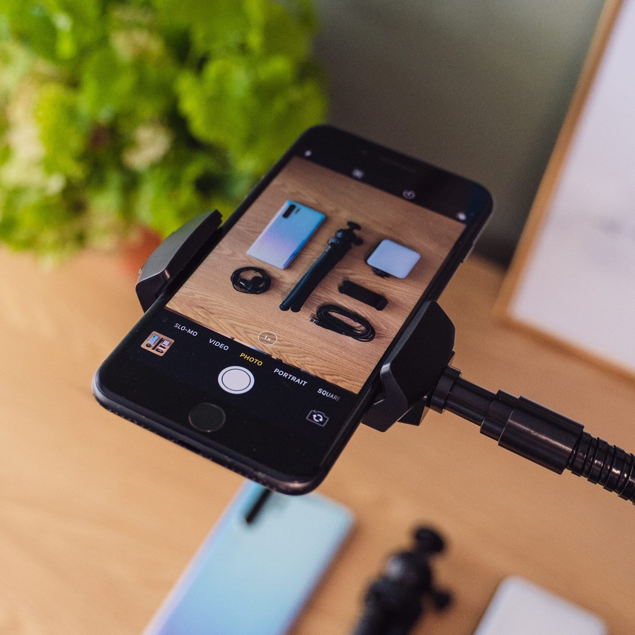 Smartphone op flexibele arm gemonteerd. Scherm toont fotoapparatuur en accessoires.