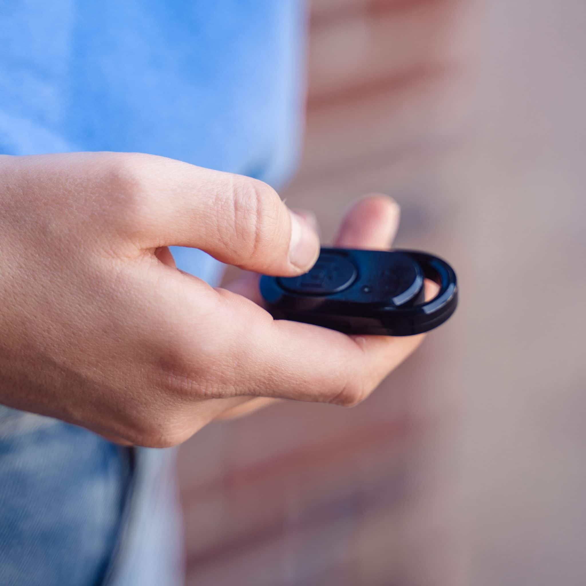 Hand holding a small black remote control.
